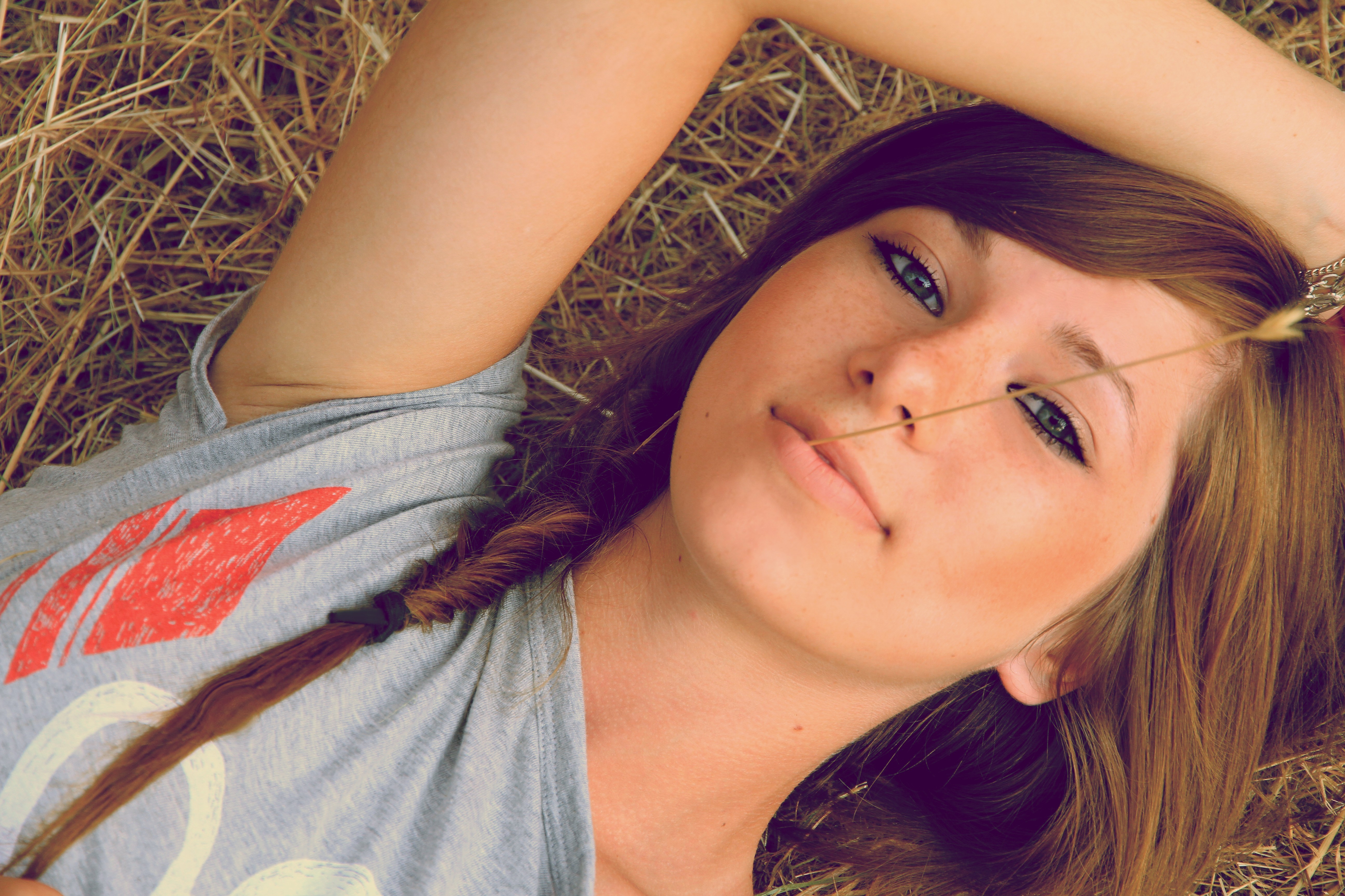 Young woman with green eyes lying in hay HD Wallpaper