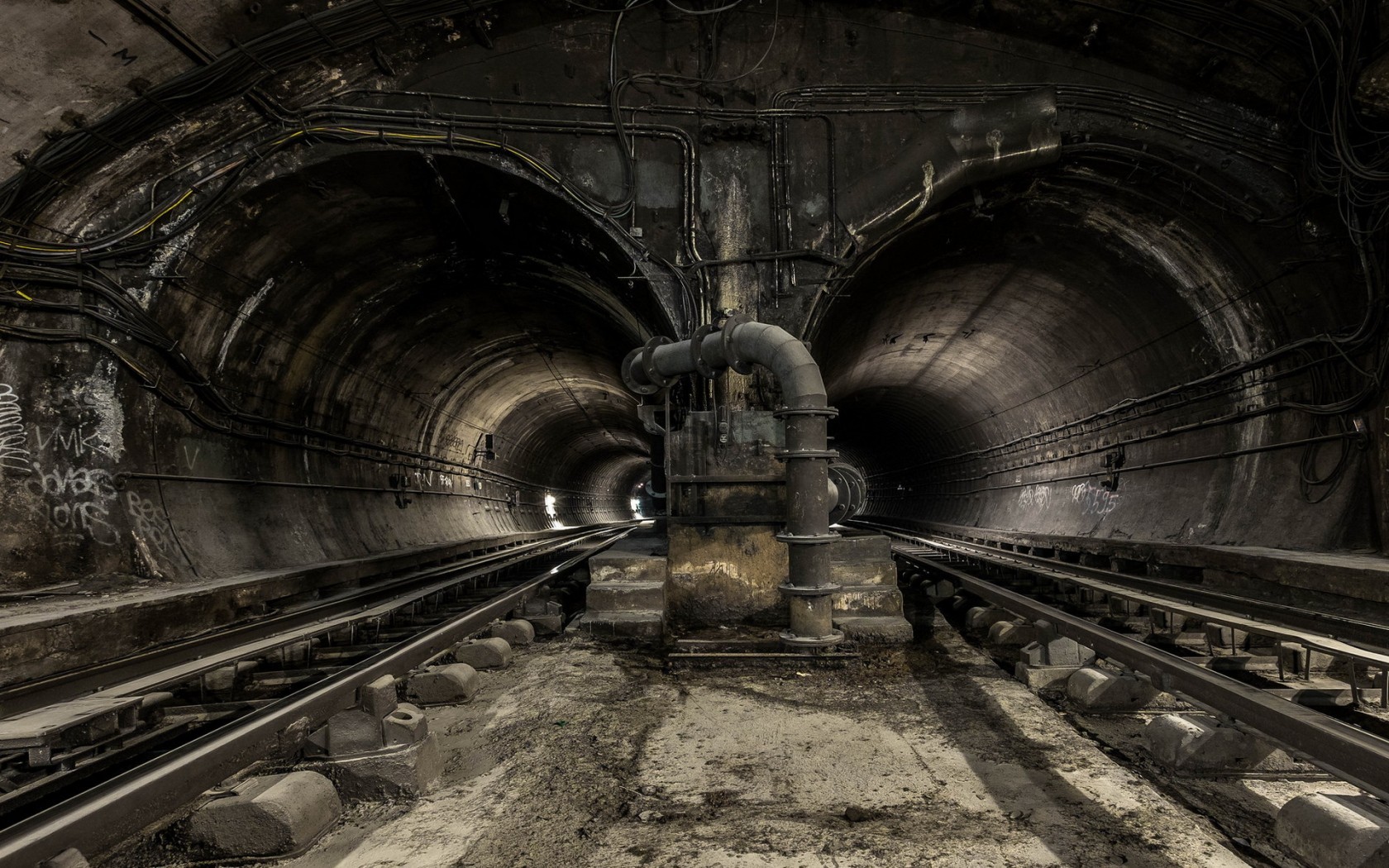 Abandoned subway tunnel with tracks and pipes HD Wallpaper