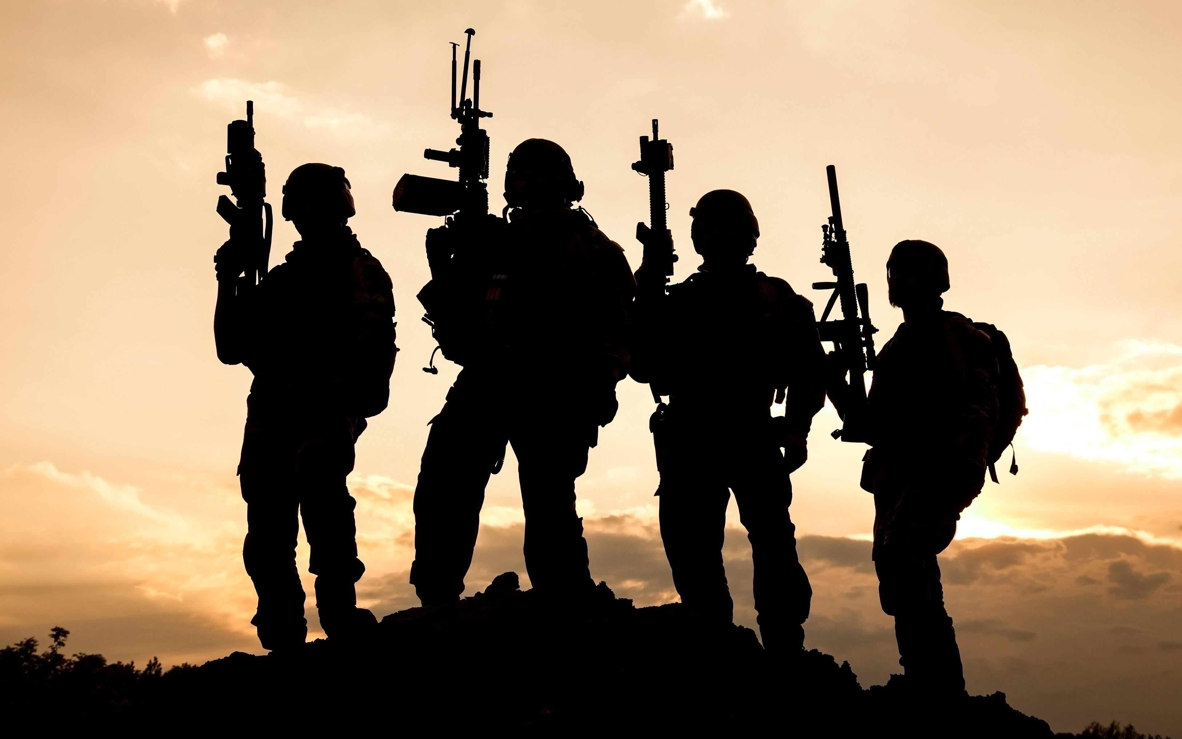Soldiers silhouetted against a sunset sky HD Wallpaper