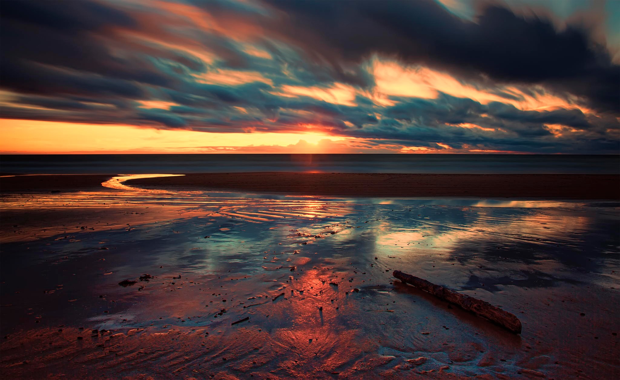 Sunset over the sea at a beach with dramatic clouds HD Wallpaper