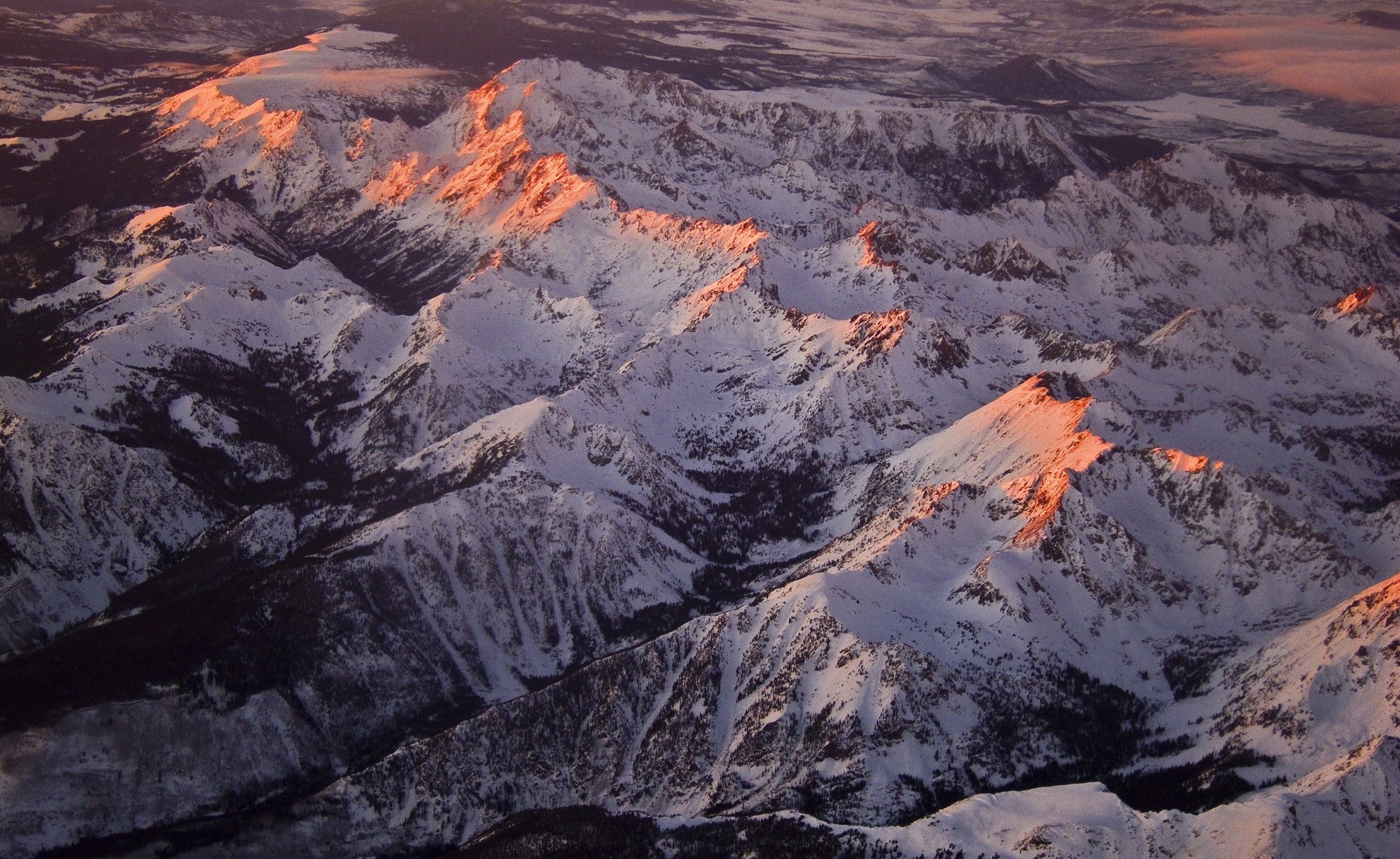 Snow-covered mountains illuminated by golden hour light HD Wallpaper