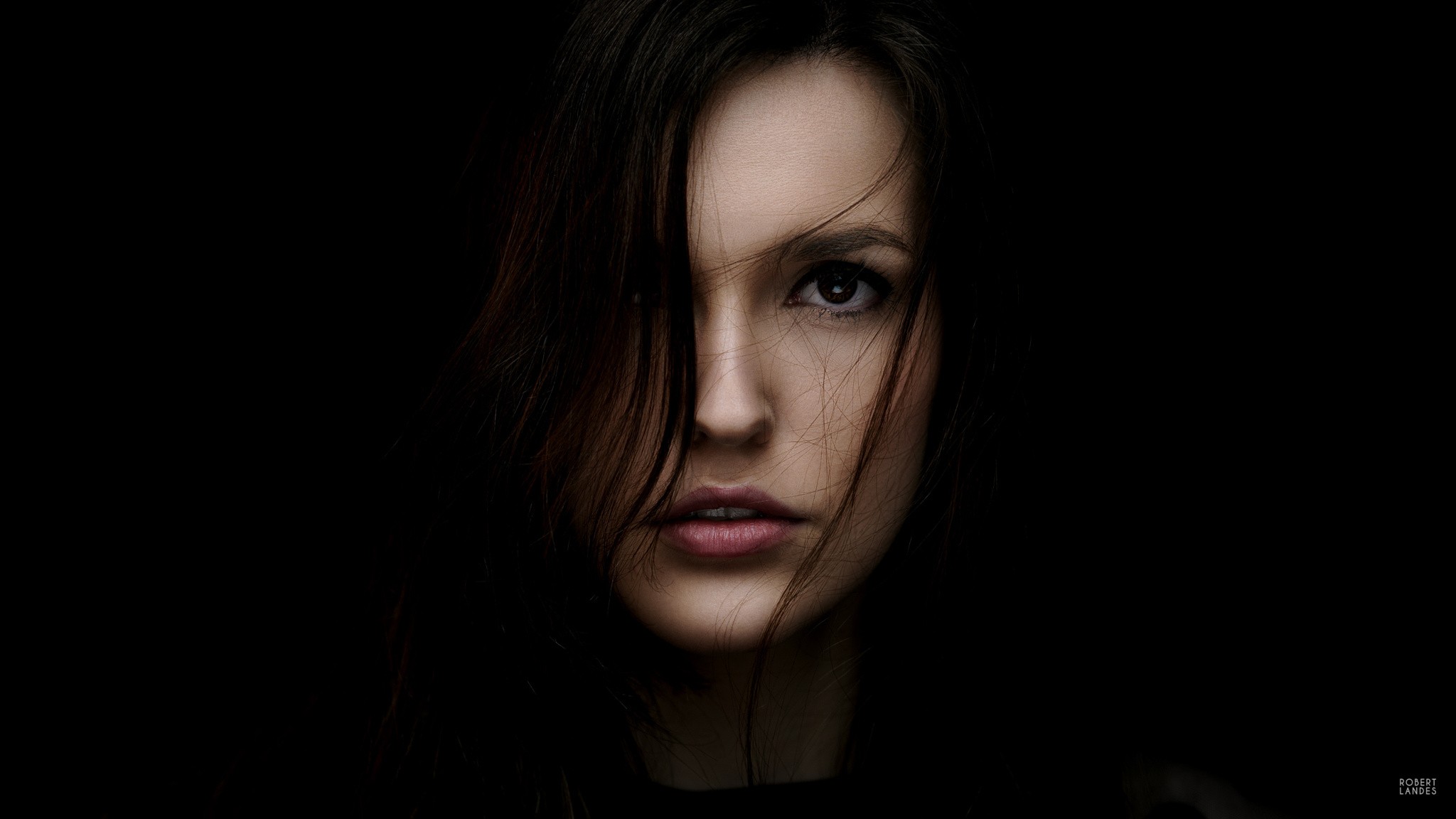 Woman with dark hair against a black background HD Wallpaper
