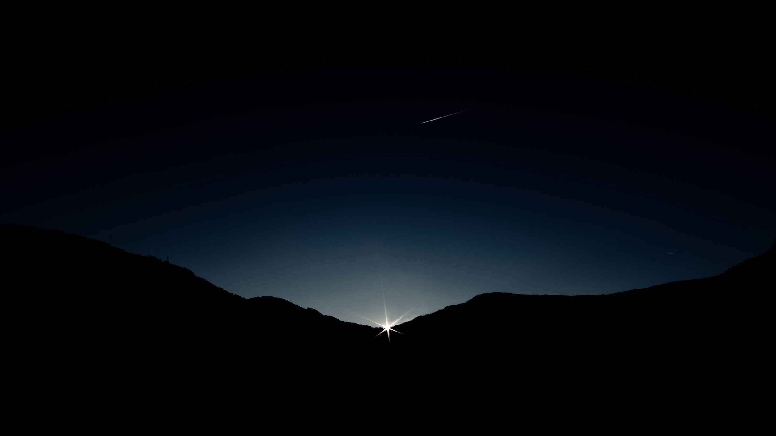 Sunrise over silhouetted mountains with a contrail HD Wallpaper