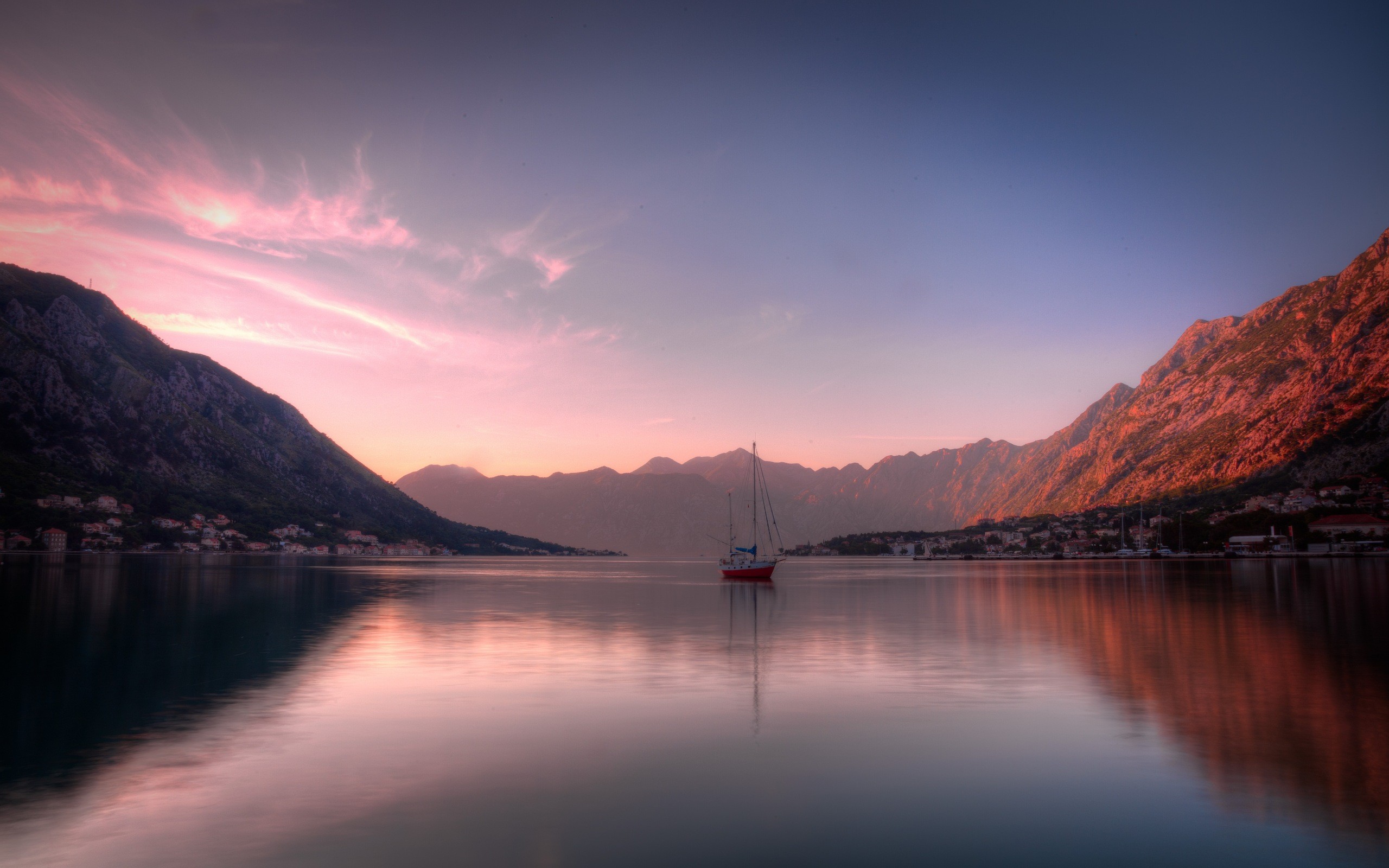 Red sailboat on a calm sea with mountains at sunset HD Wallpaper