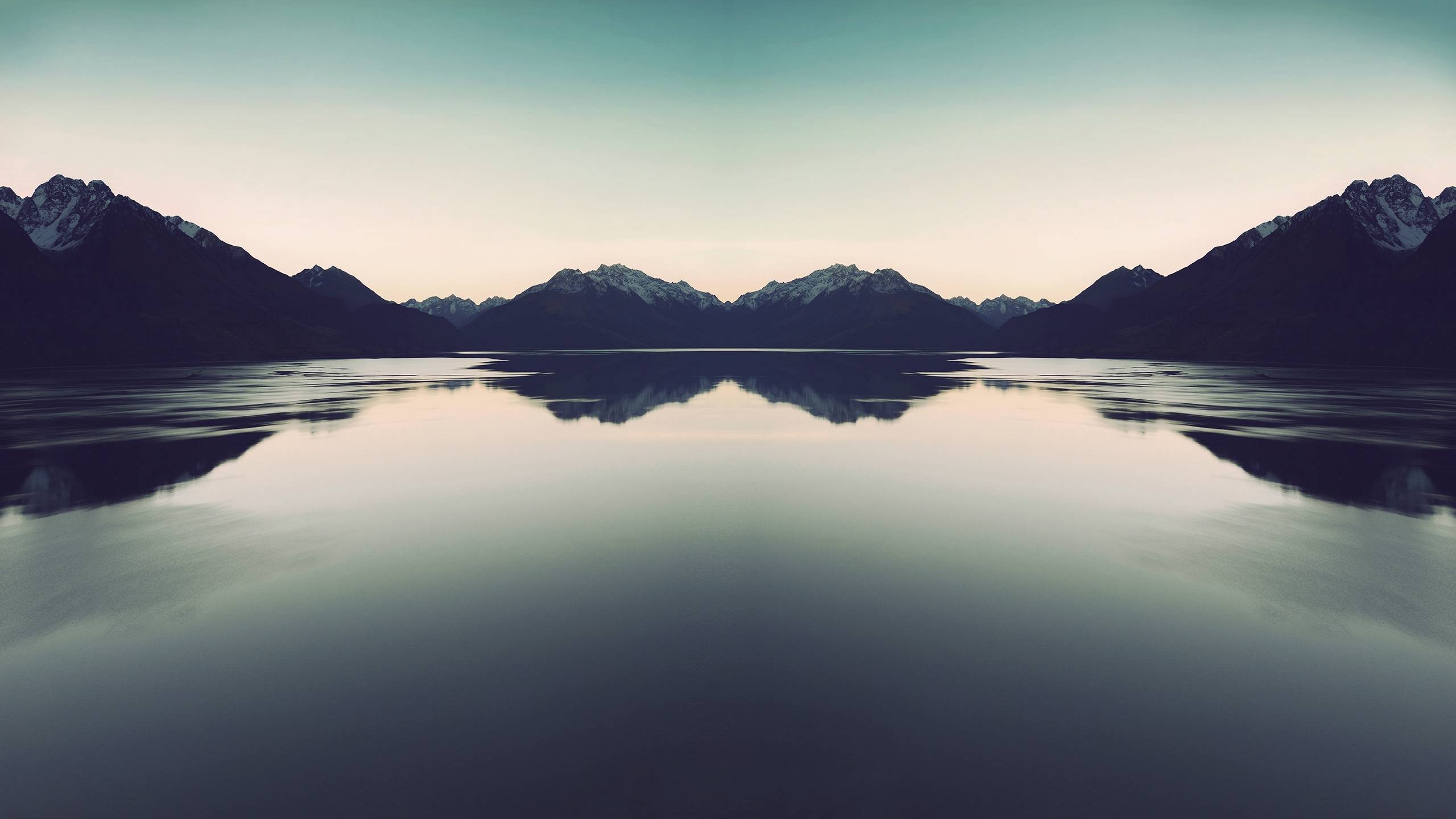 Mirror image of mountains reflected in a calm lake HD Wallpaper