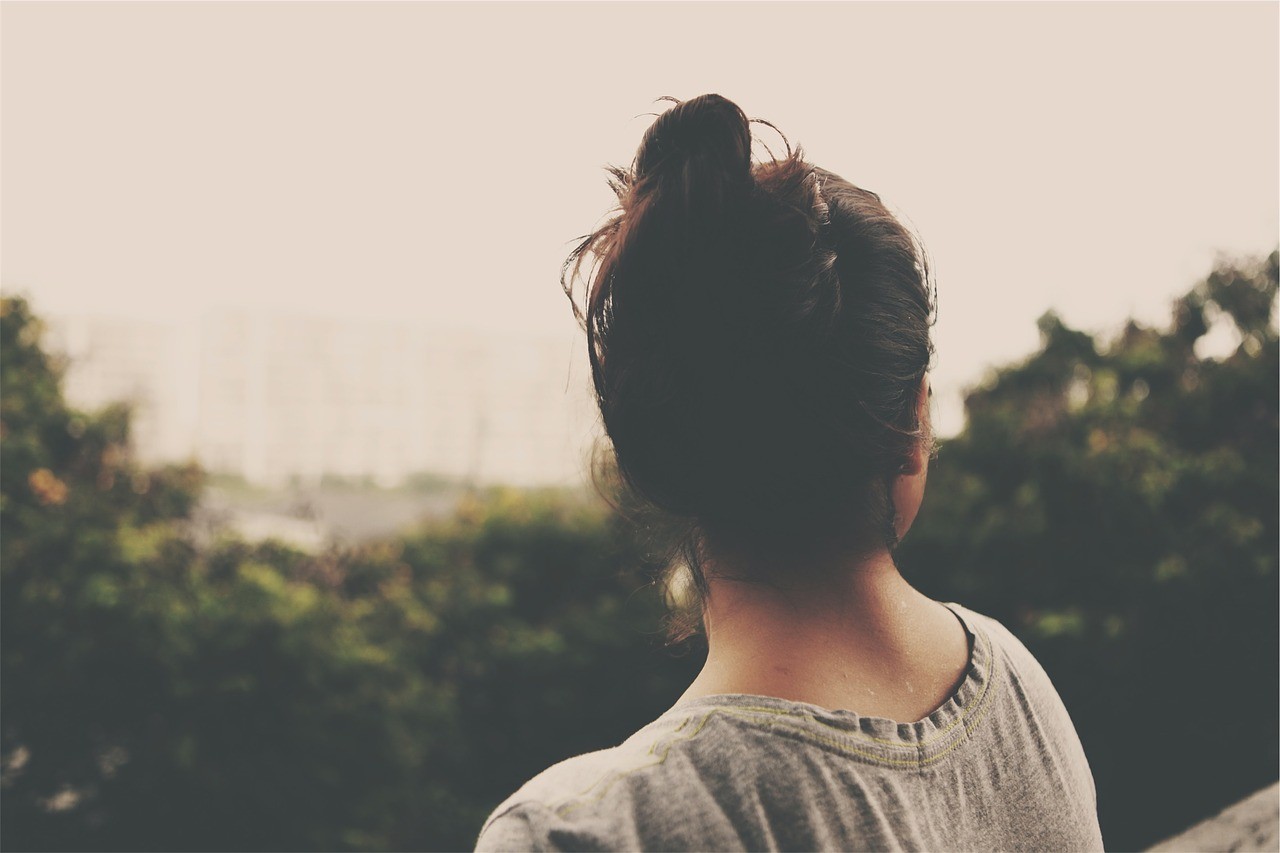 Woman with dark hair in a bun looking away HD Wallpaper