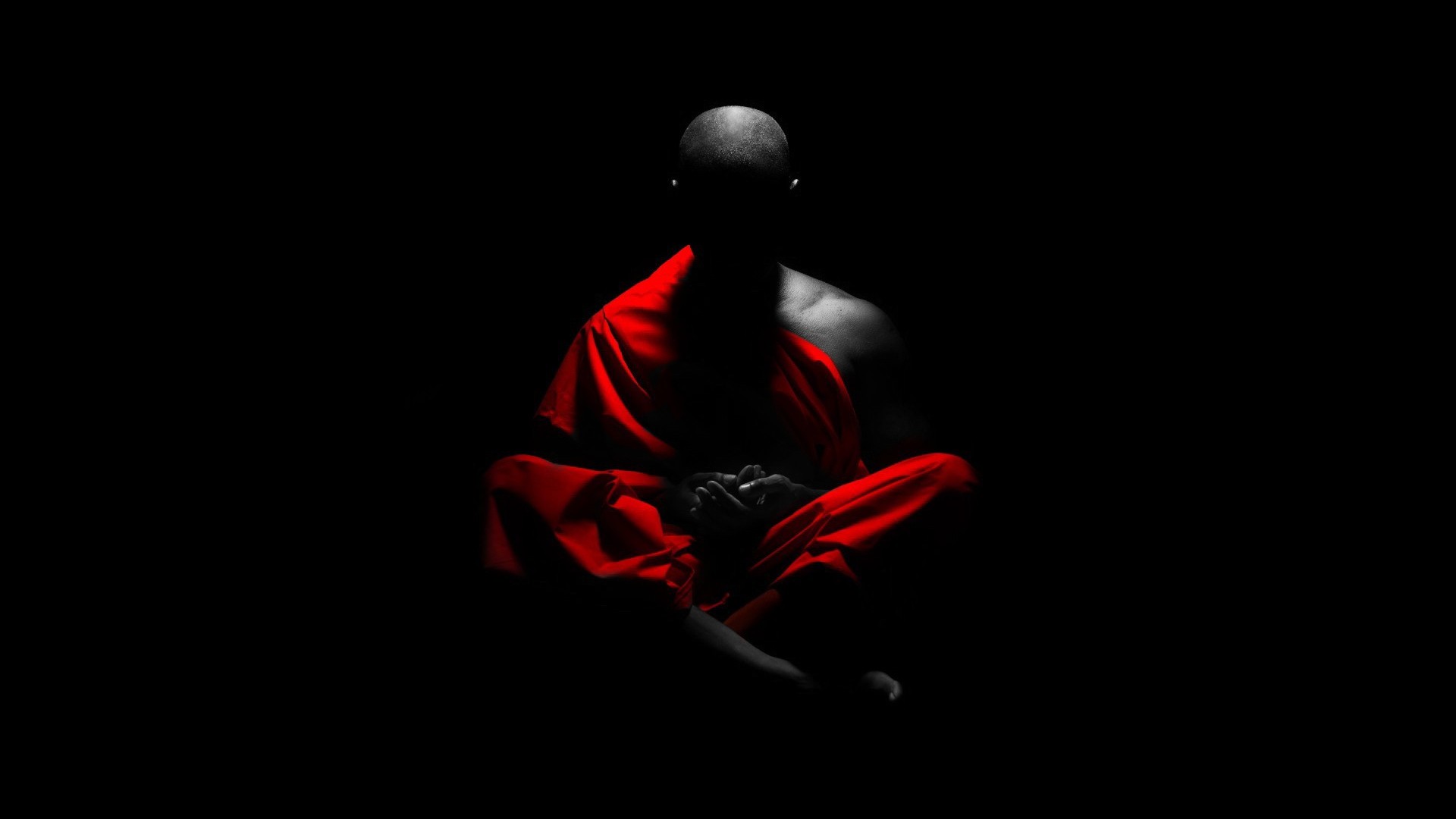 Monk meditating in red robes on black background HD Wallpaper