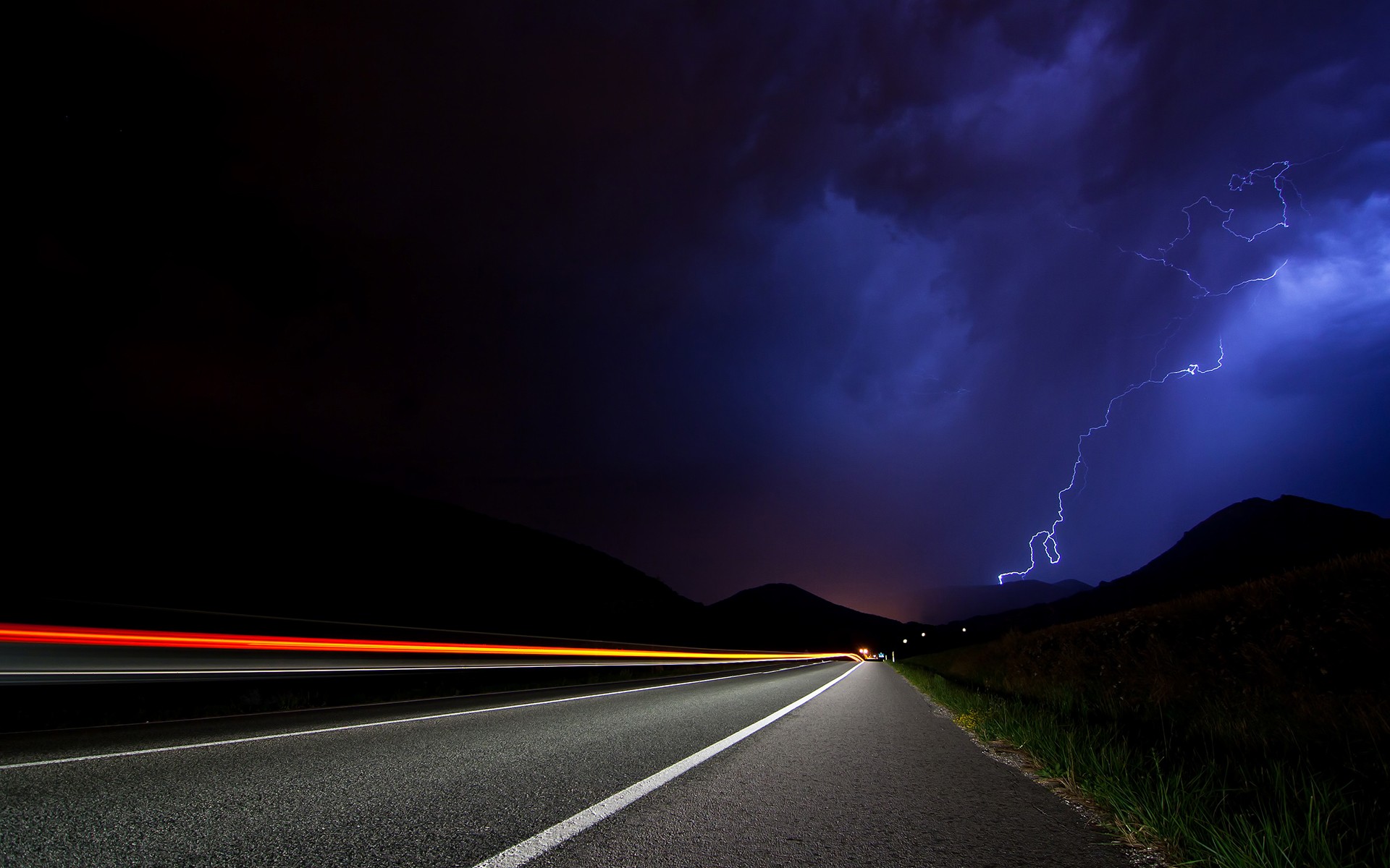 Lightning strikes over a road at night with light trails HD Wallpaper