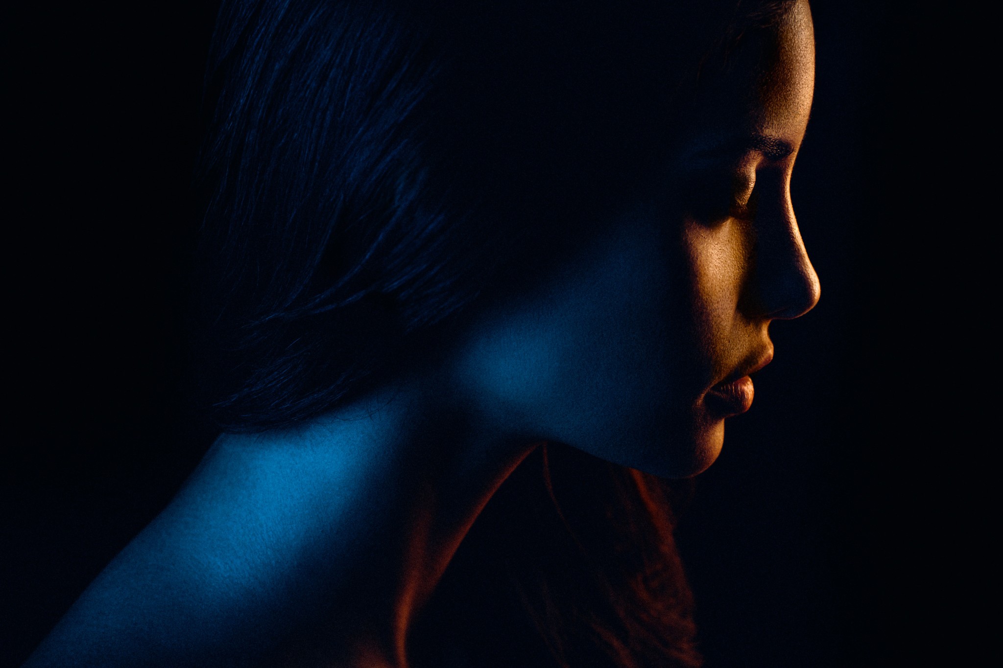 Profile of a woman lit by blue and orange light HD Wallpaper