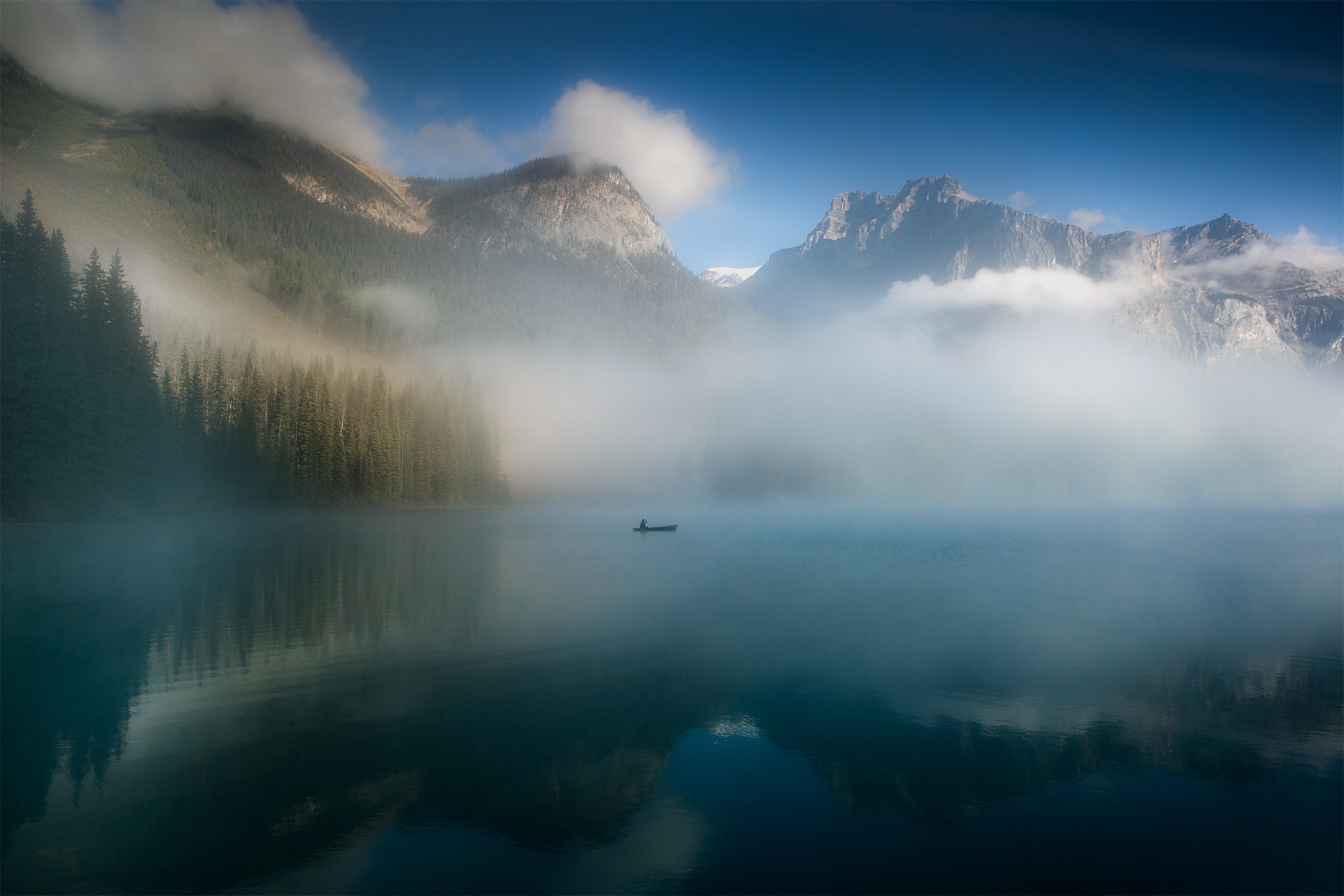 A lone canoeist on a misty lake with mountains HD Wallpaper