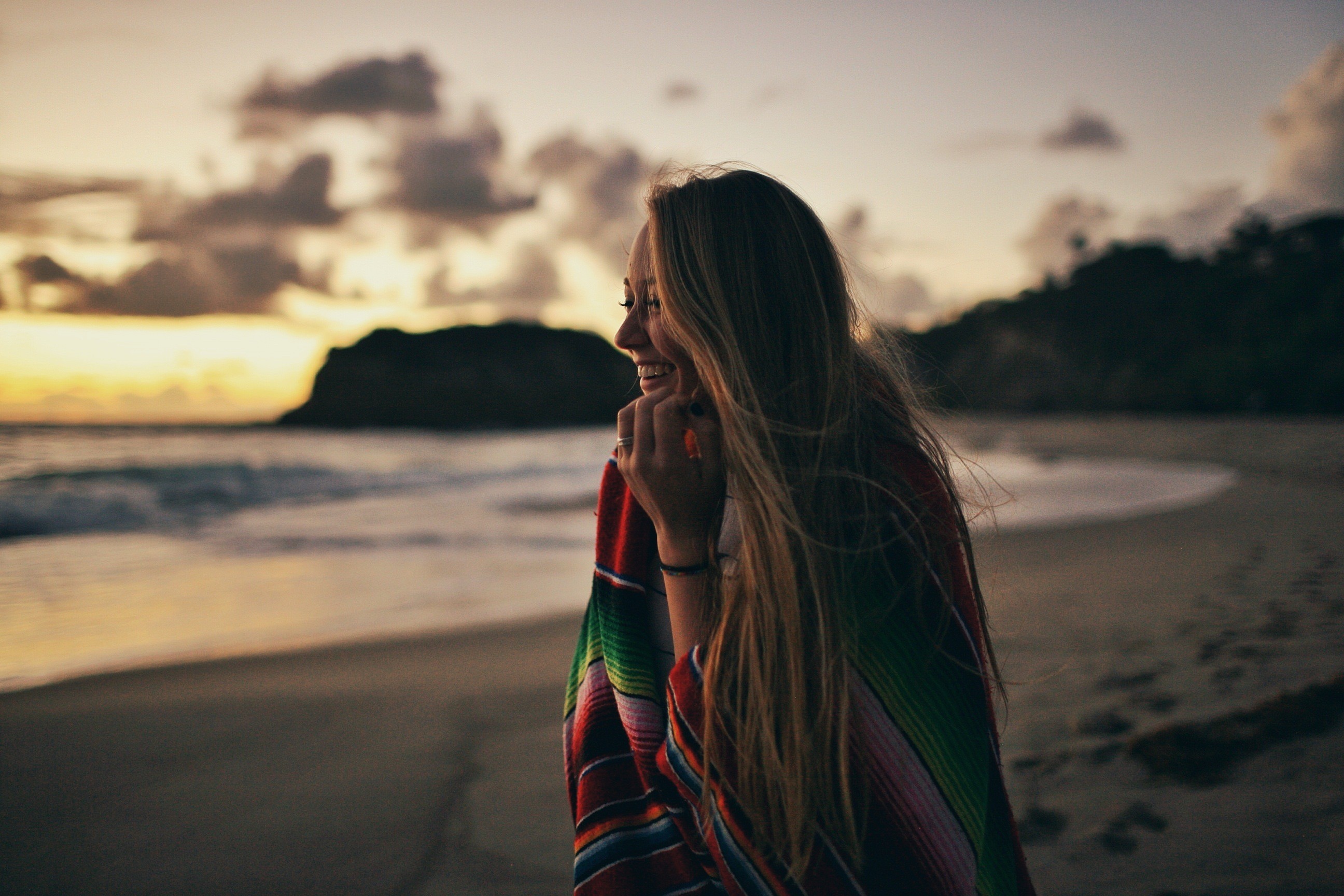 Woman wrapped in a colorful blanket on a beach at sunset HD Wallpaper