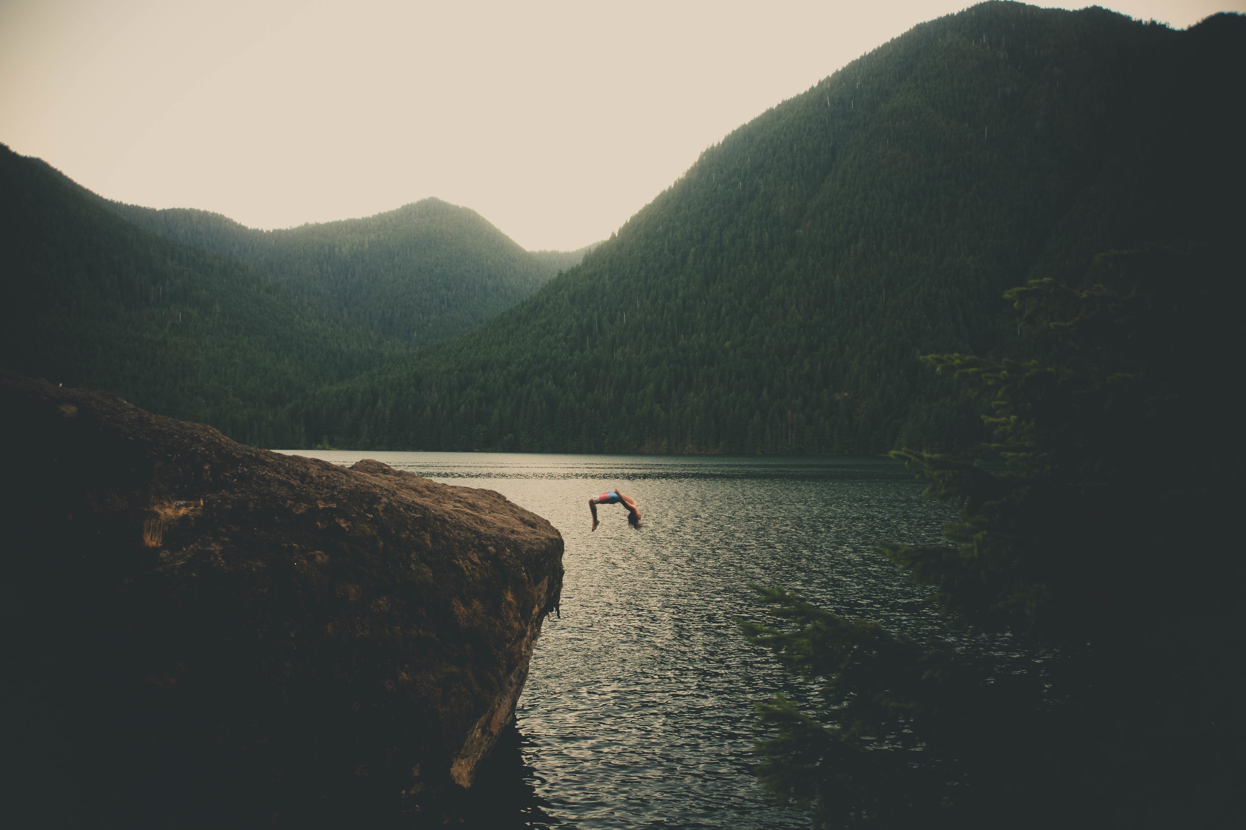 Person doing a flip off a rock into a lake HD Wallpaper