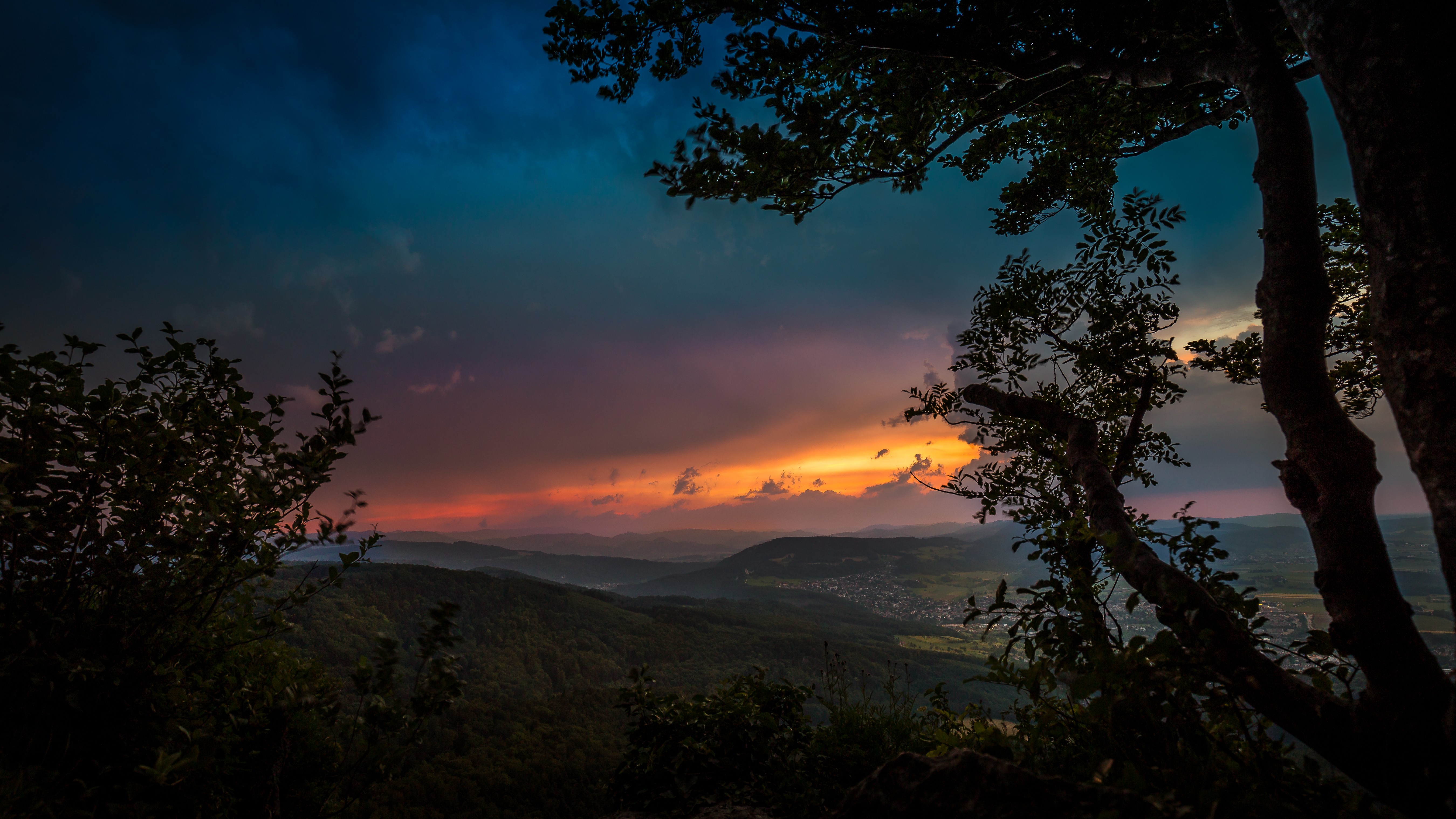 Sunset over a valley with trees in the foreground HD Wallpaper
