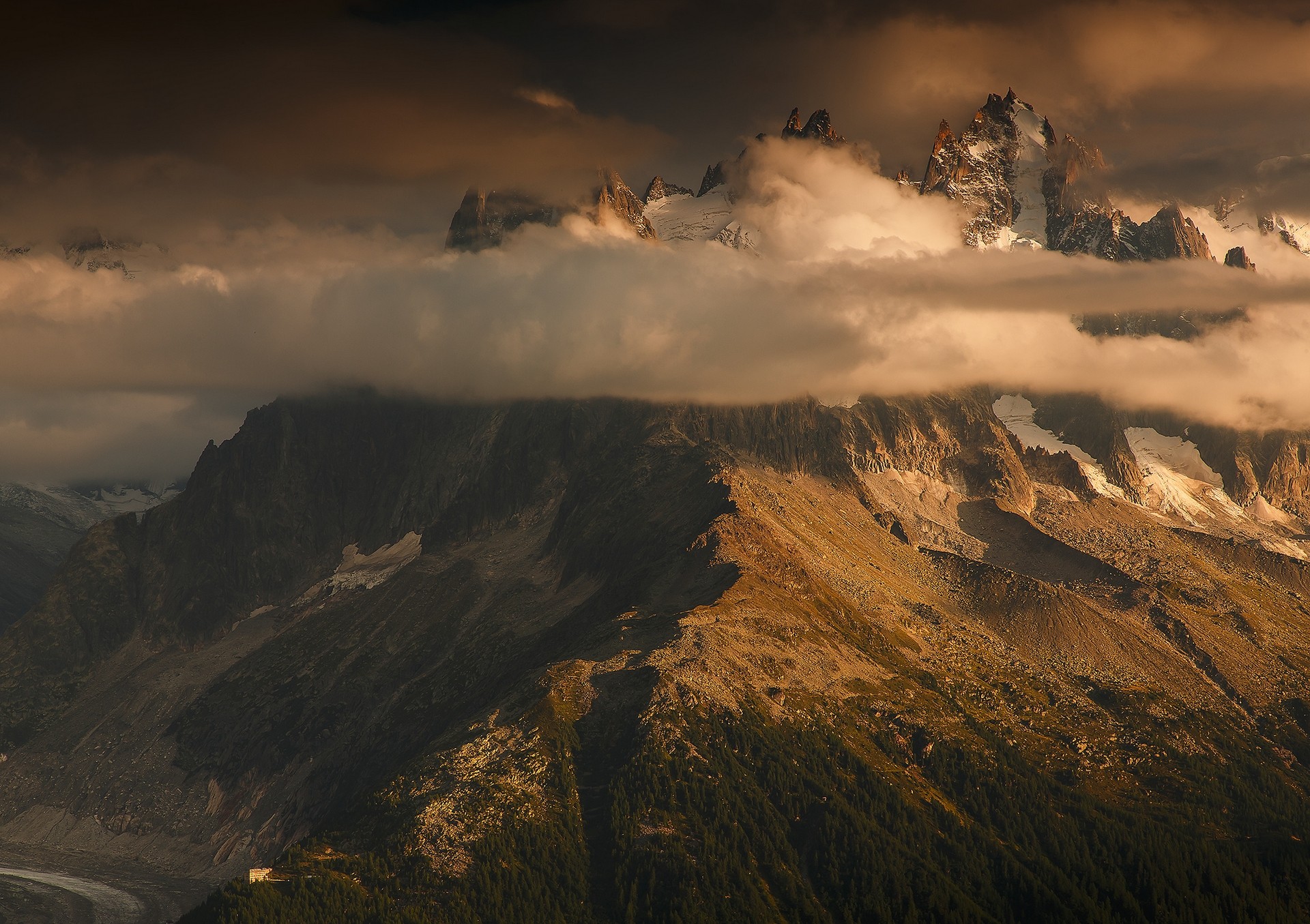 Dramatic mountain range shrouded in clouds at sunset HD Wallpaper