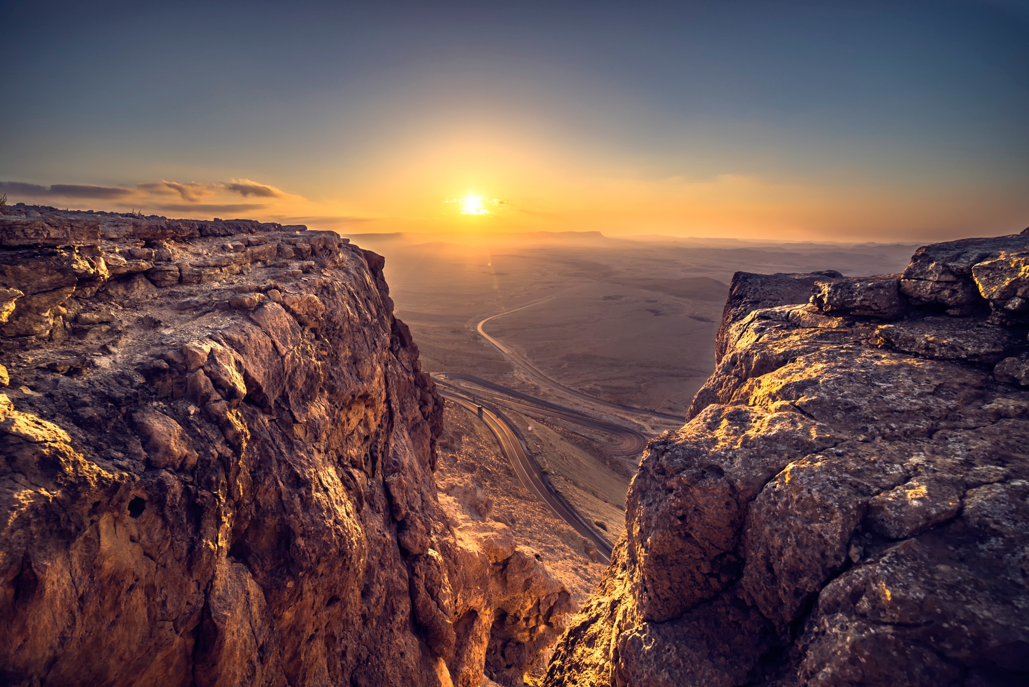 Sunset over a rocky desert landscape with a road HD Wallpaper