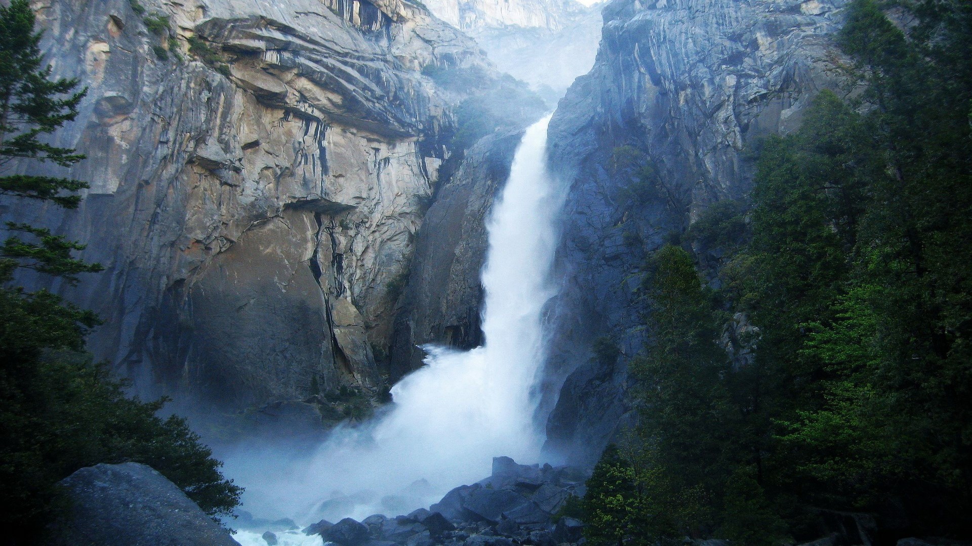 Waterfall cascading down a rocky cliff face HD Wallpaper