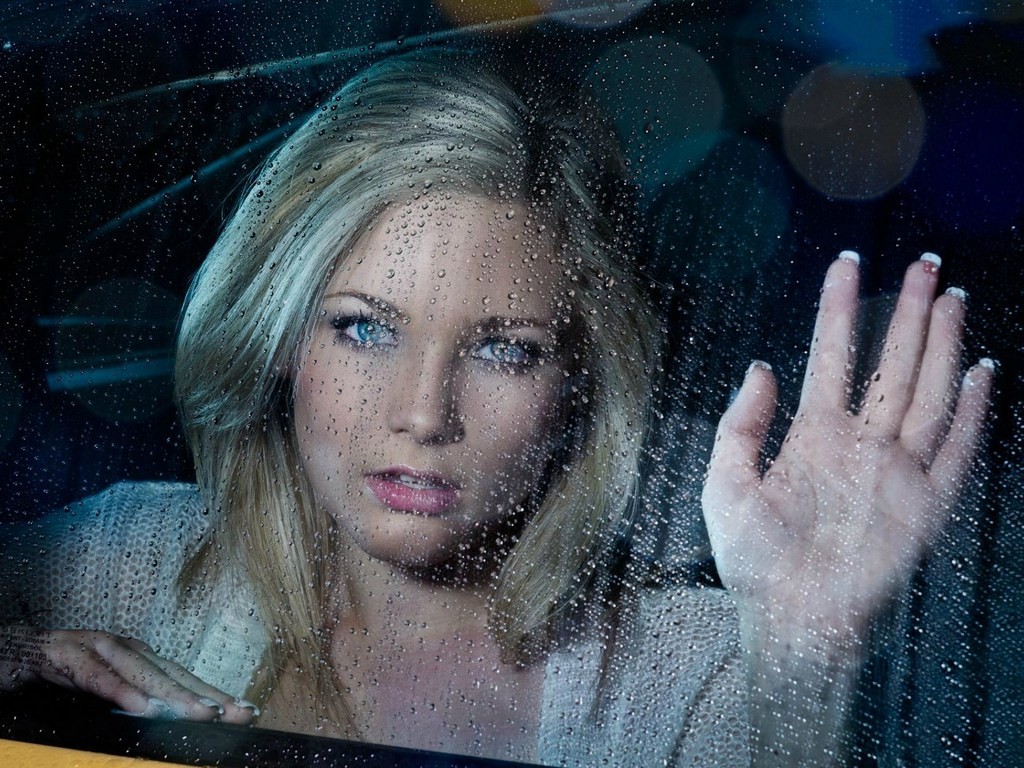 Woman with blonde hair and blue eyes looking through a rainy window HD Wallpaper