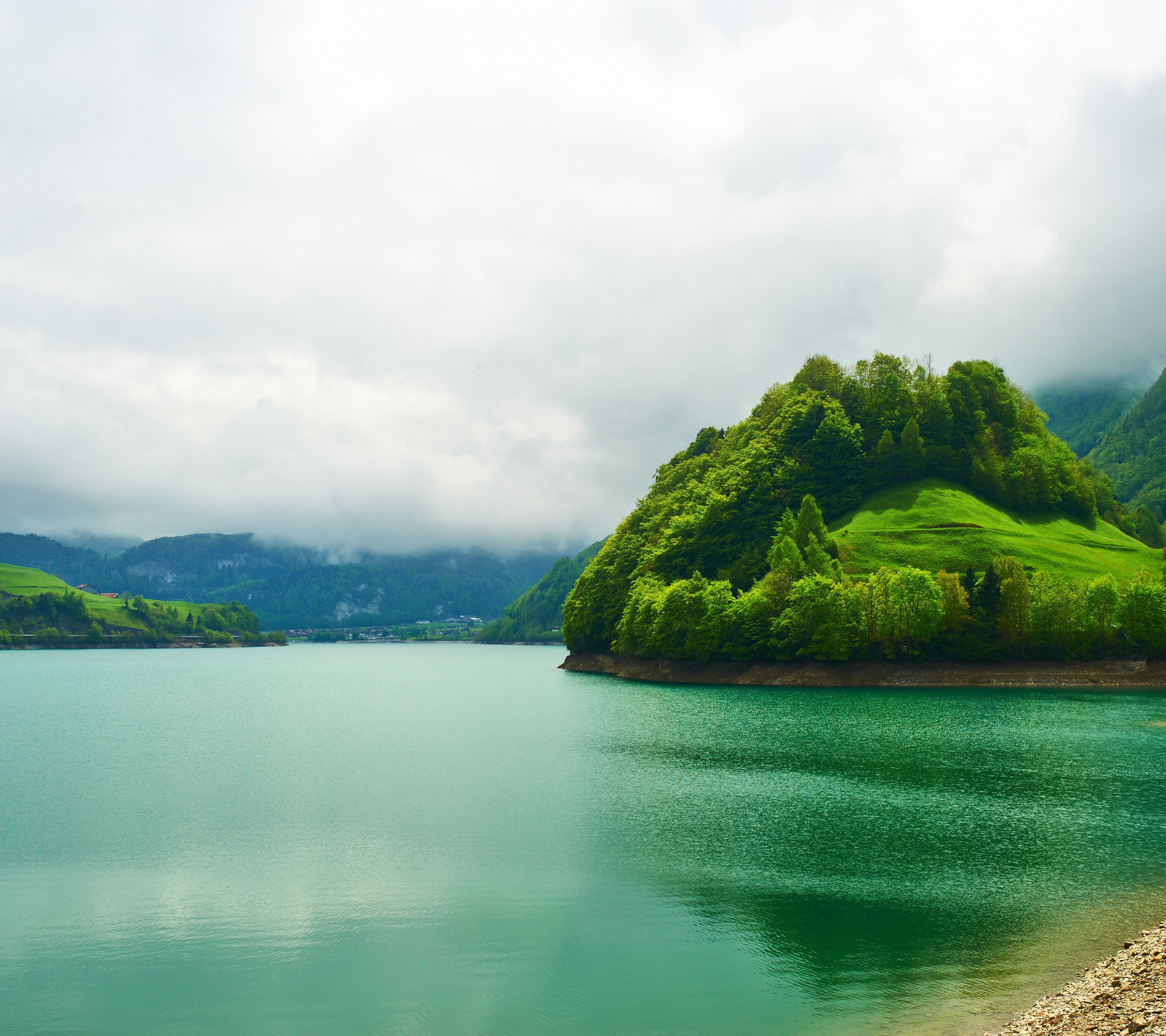 Green island in a turquoise lake with cloudy sky HD Wallpaper
