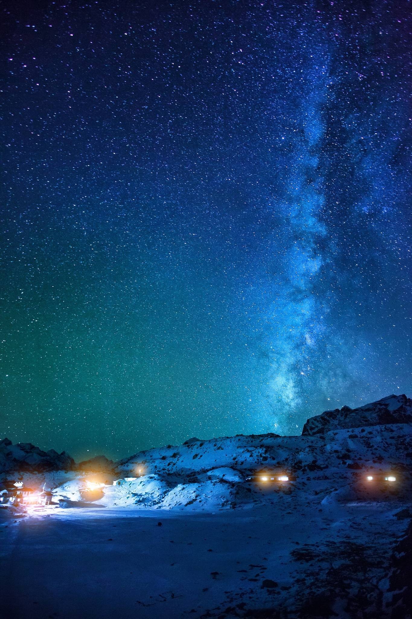 Starry night sky over a snowy landscape with lights HD Wallpaper