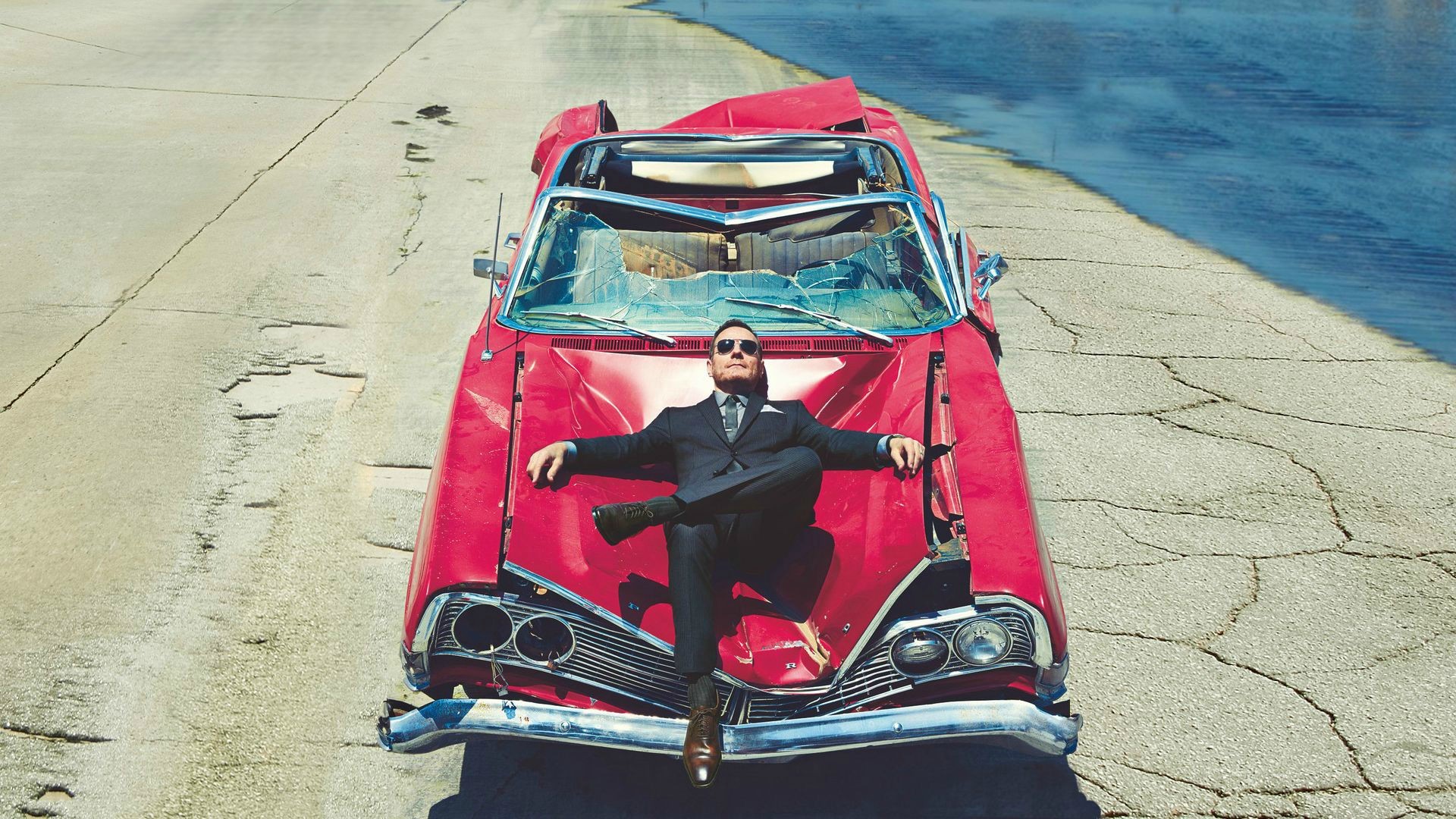 Bryan Cranston in a suit on a damaged car HD Wallpaper