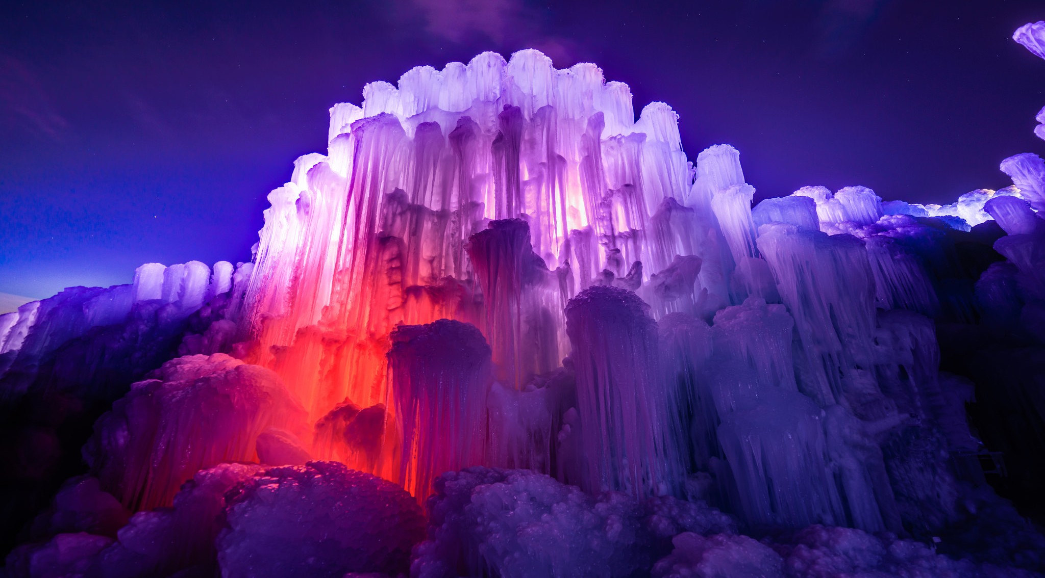 Ice castle illuminated with colorful lights at night HD Wallpaper