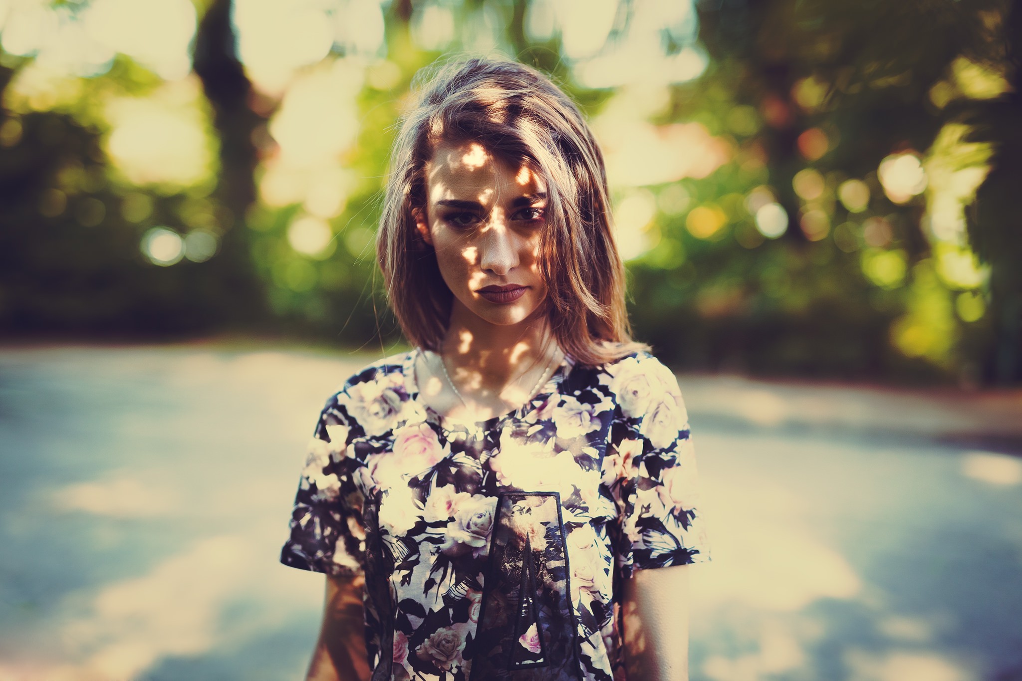 Woman in floral shirt with dappled light on face HD Wallpaper
