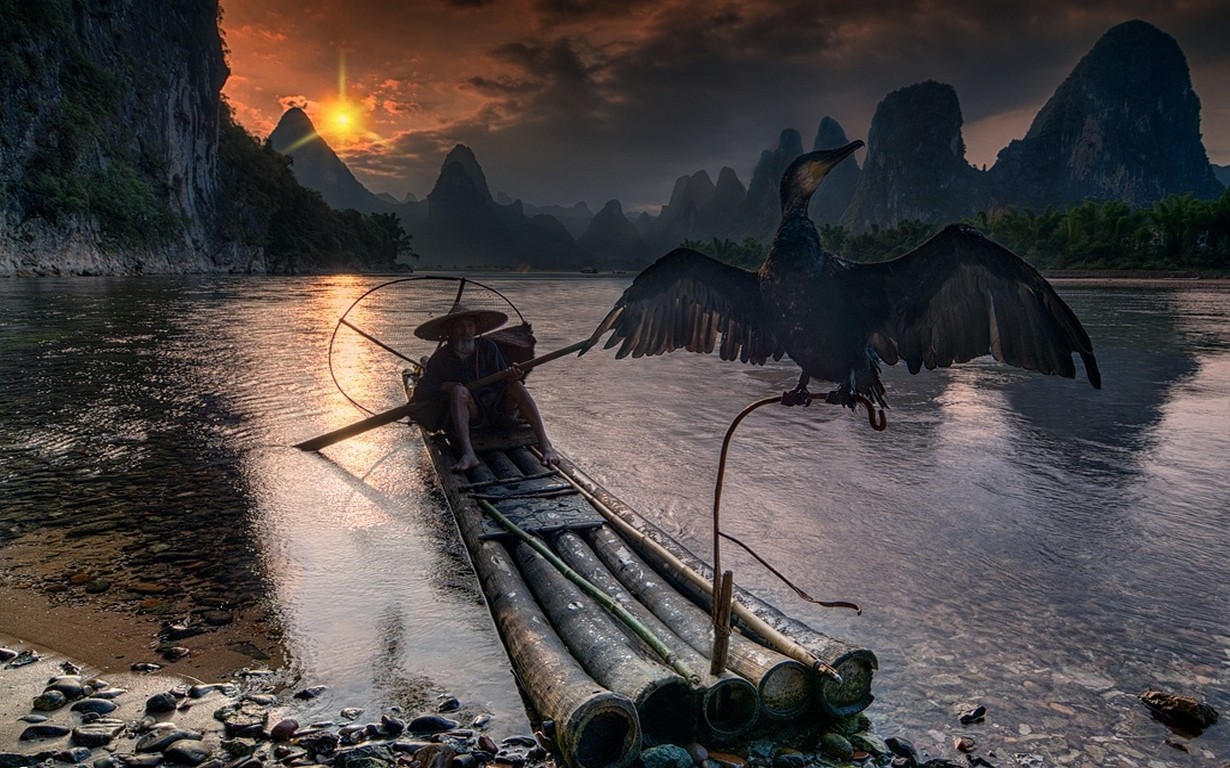 Fisherman and cormorant on a boat at sunset in Guilin HD Wallpaper