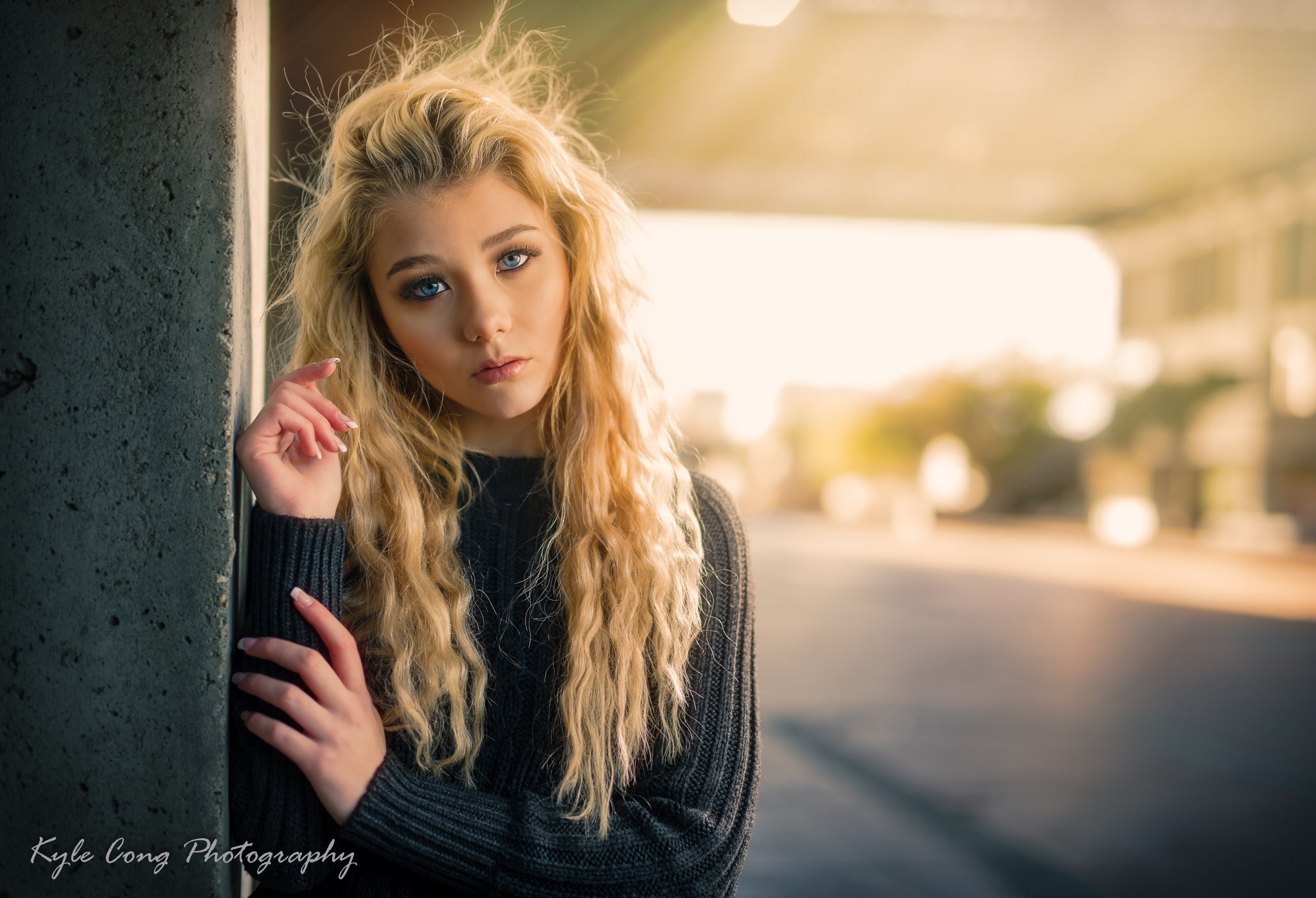 Woman with blonde curly hair leaning against a pillar HD Wallpaper