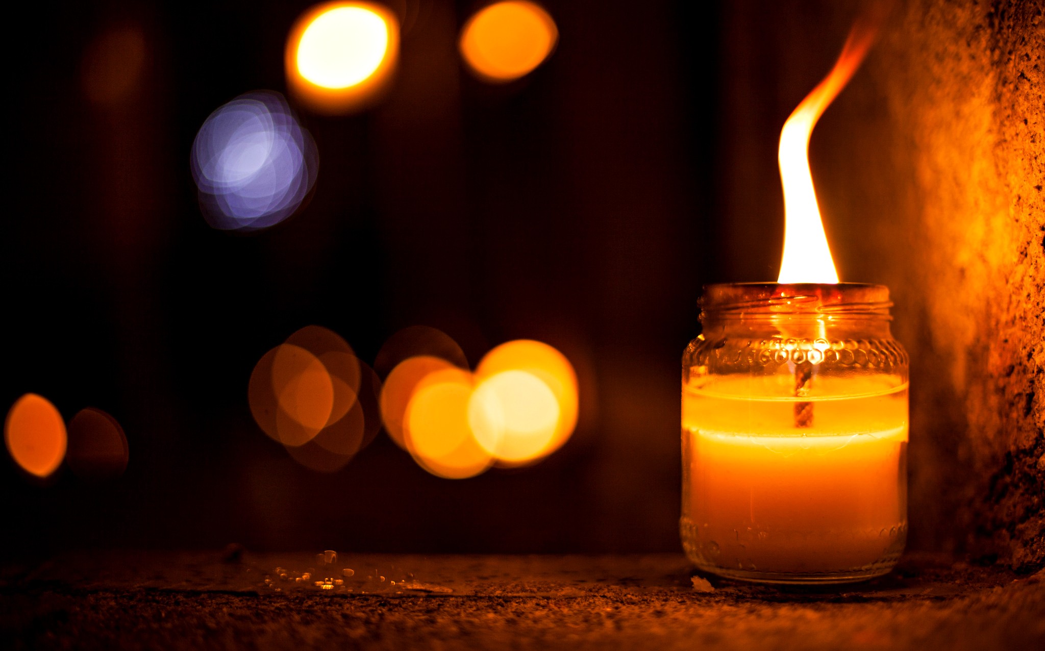 Candle burning in a jar with bokeh lights HD Wallpaper