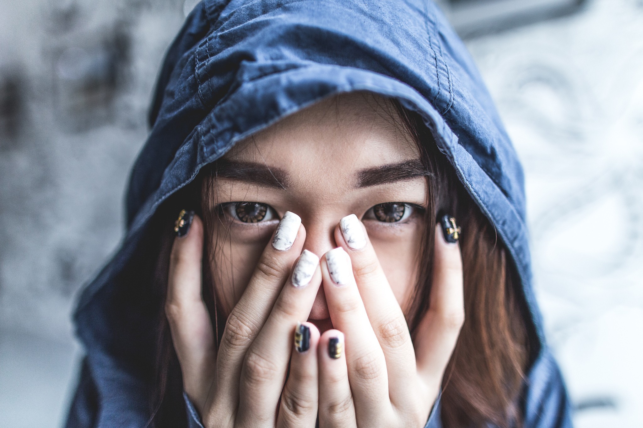 Woman hiding face with hands under blue hood HD Wallpaper