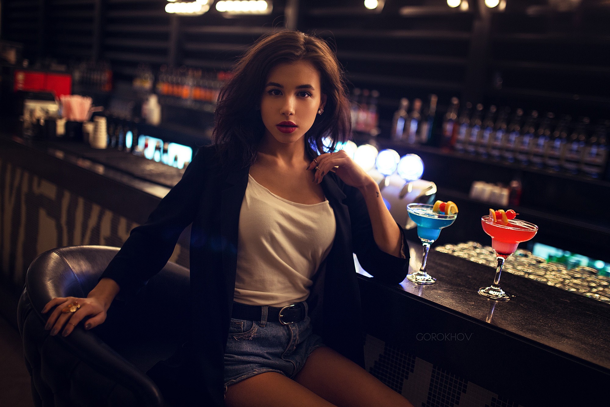 Woman in a black blazer and denim shorts at a bar HD Wallpaper