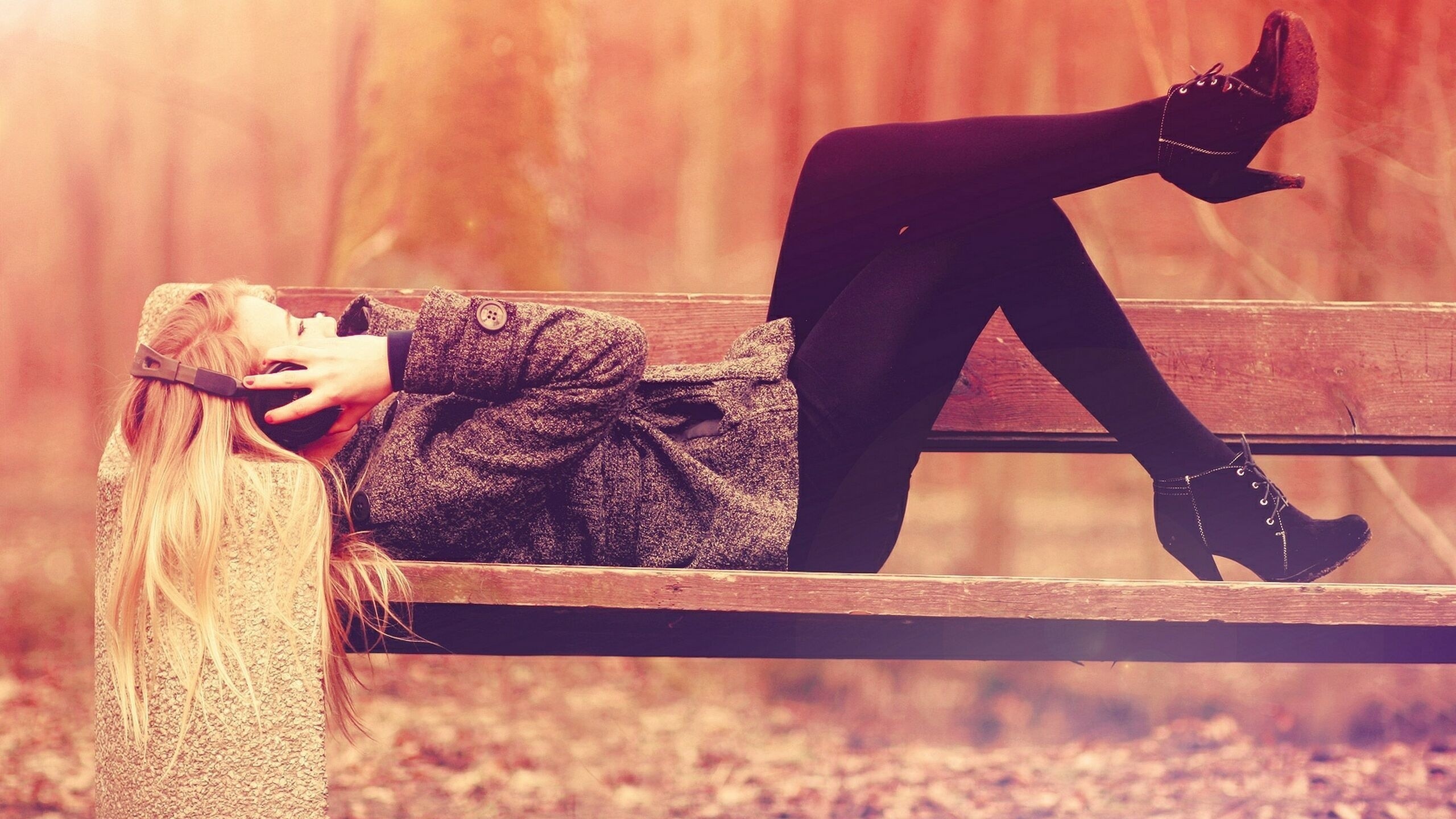 Woman with blonde hair listening to music on a bench HD Wallpaper