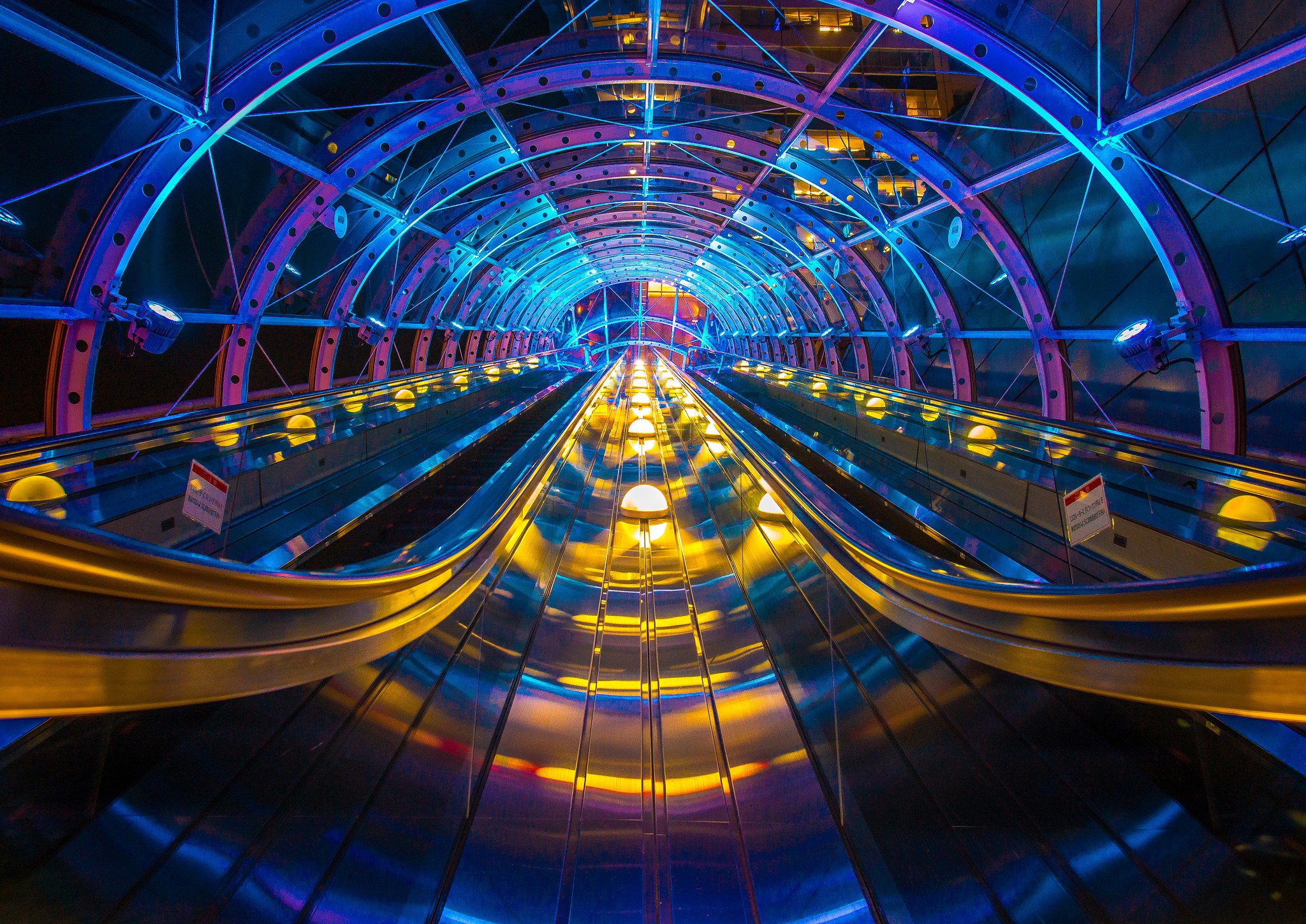 Escalator tunnel with colorful blue and yellow lights HD Wallpaper