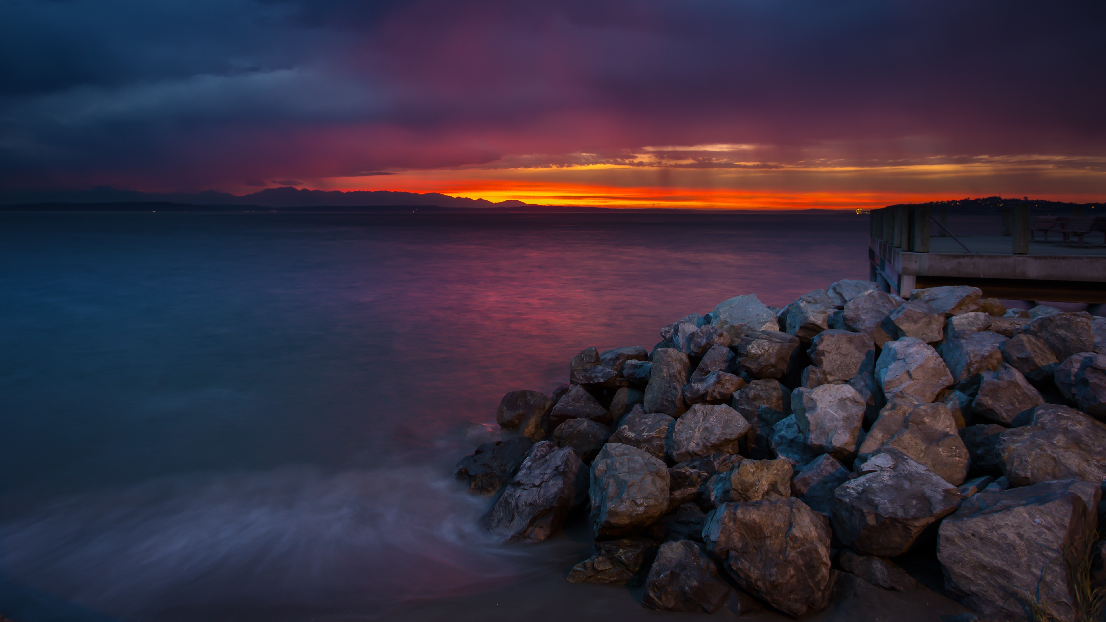 Sunset over the sea with rocks and a pier HD Wallpaper