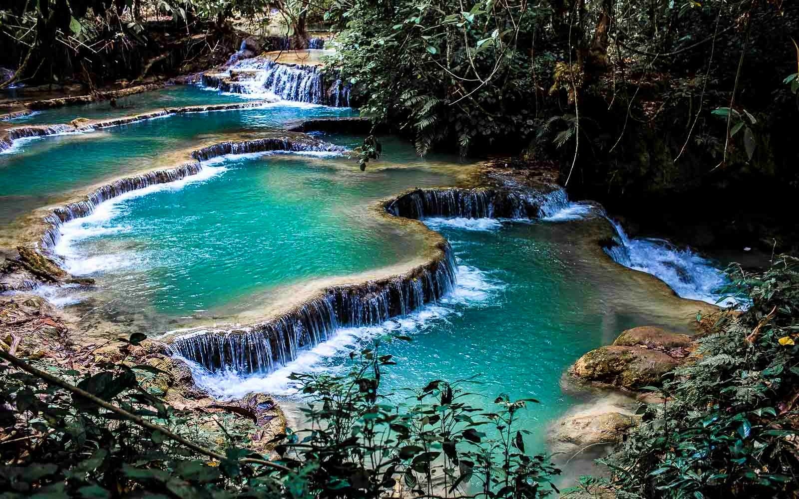 Turquoise waterfalls cascading over limestone terraces in Laos HD Wallpaper