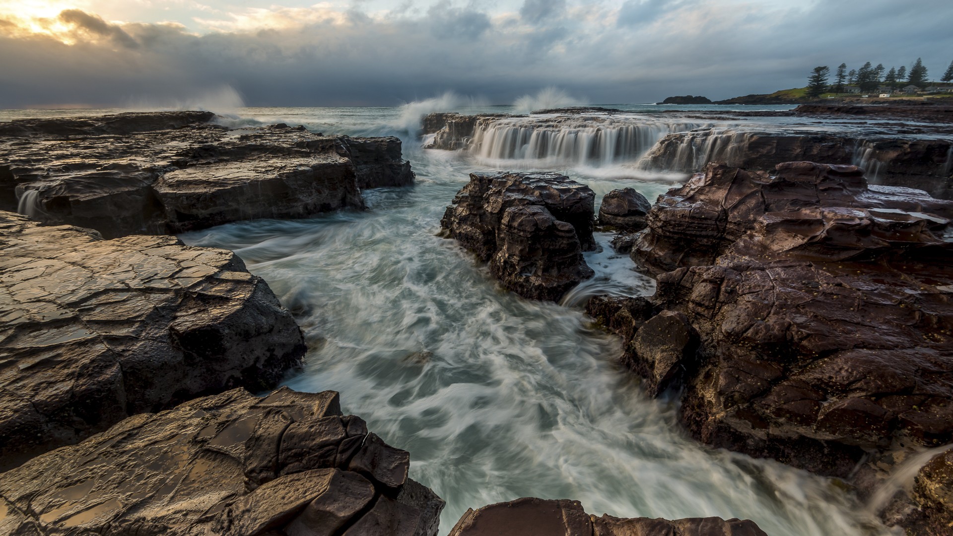 Ocean waves crashing over rocks with a waterfall HD Wallpaper