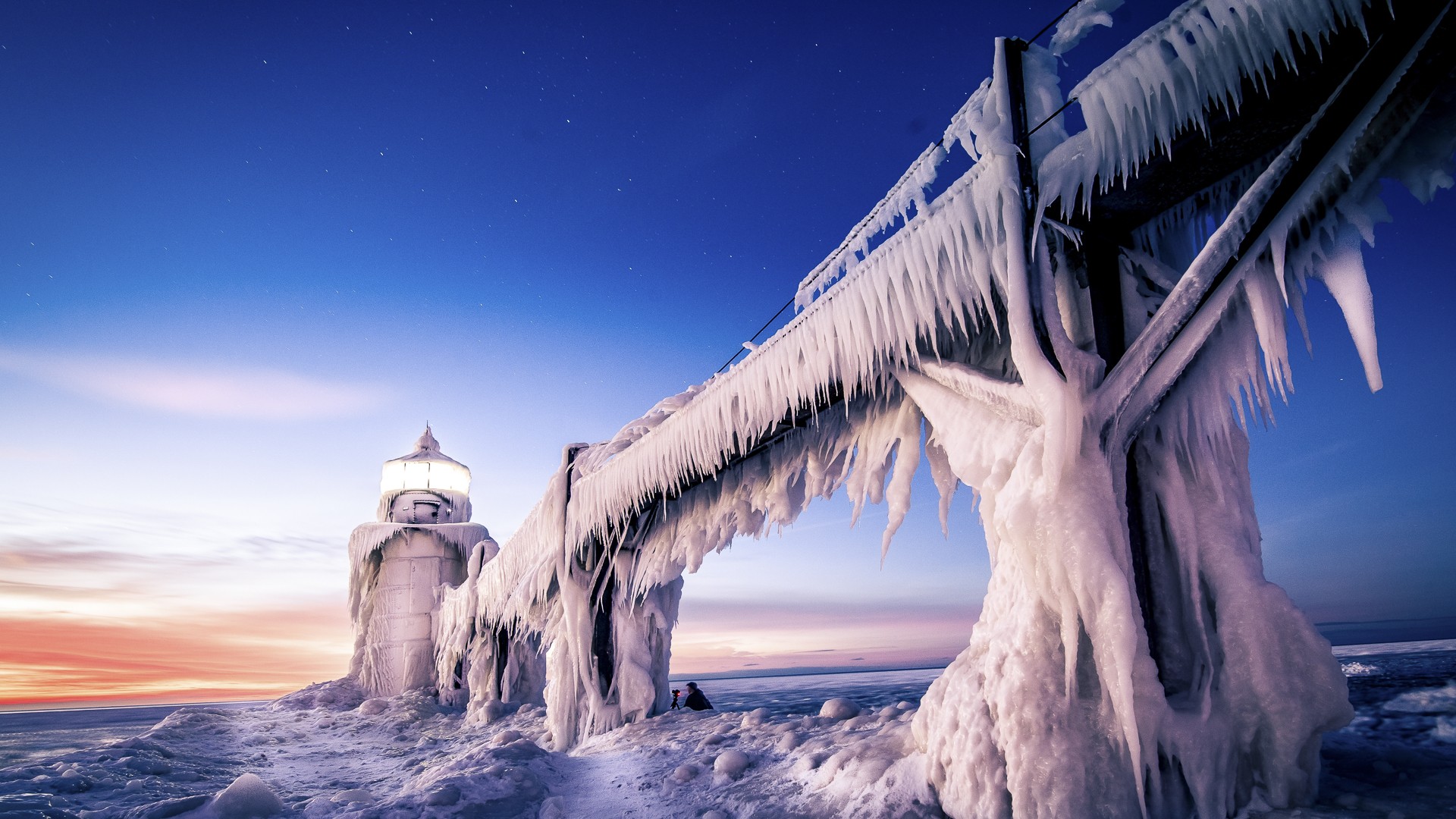 Frozen lighthouse and pier covered in ice at sunset HD Wallpaper