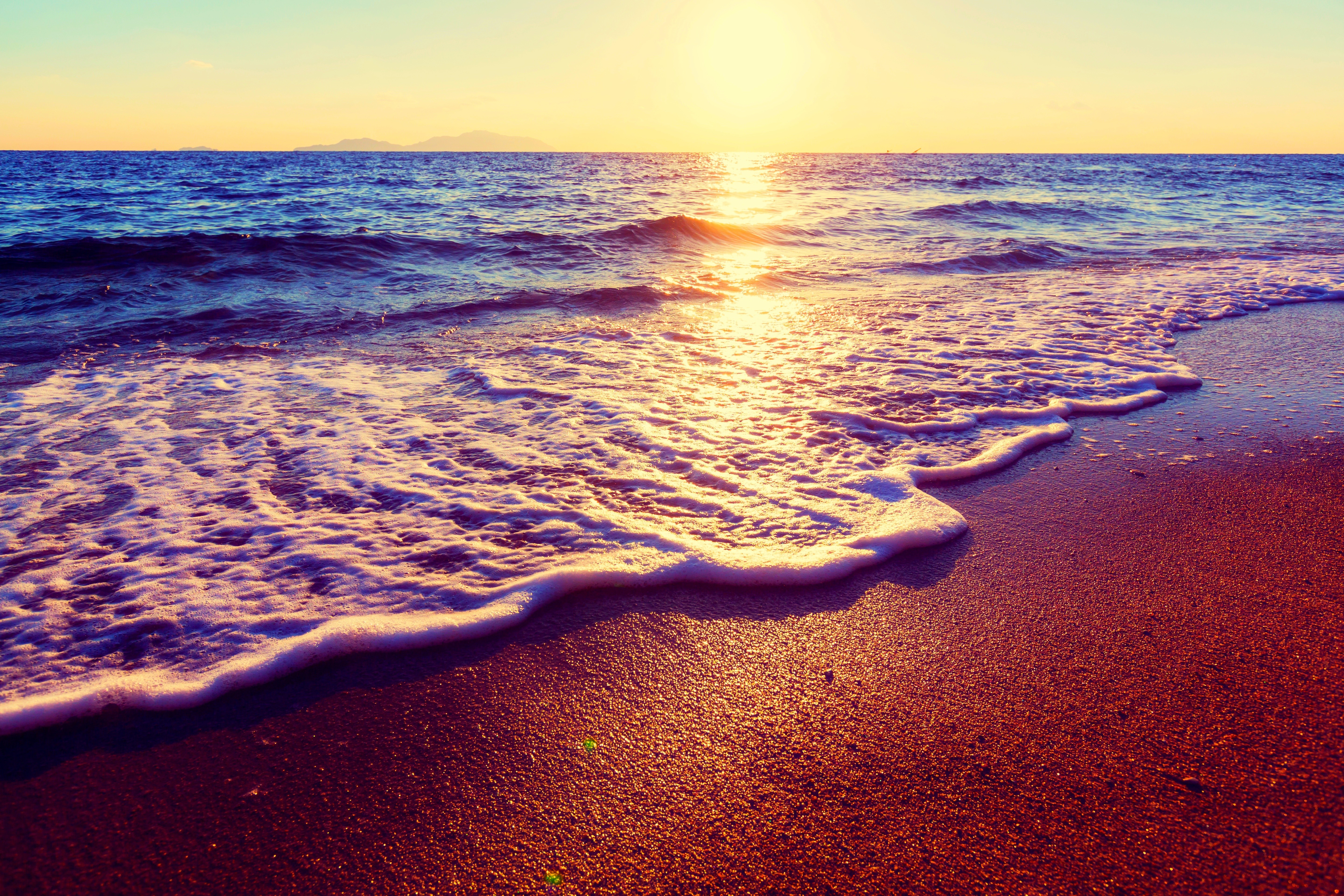 Sunset over the ocean waves on a beach HD Wallpaper