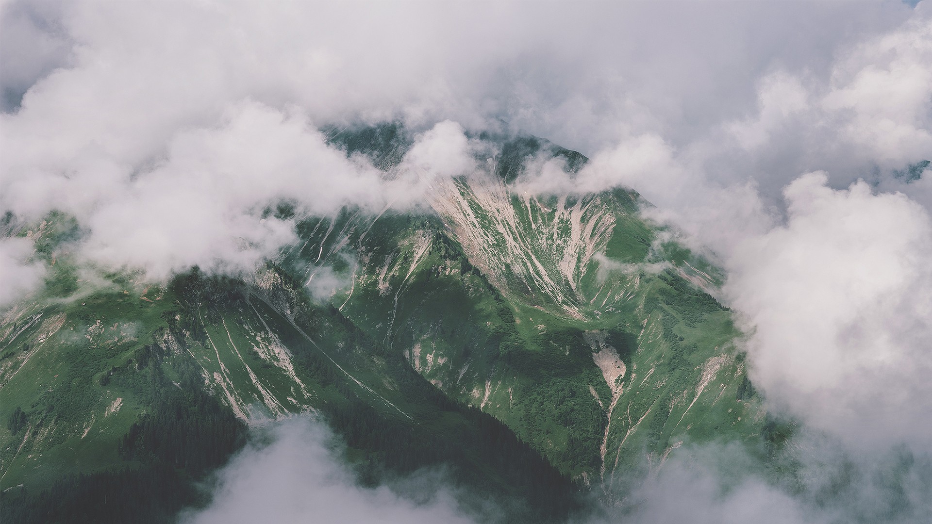 Clouds obscuring a green mountain landscape HD Wallpaper