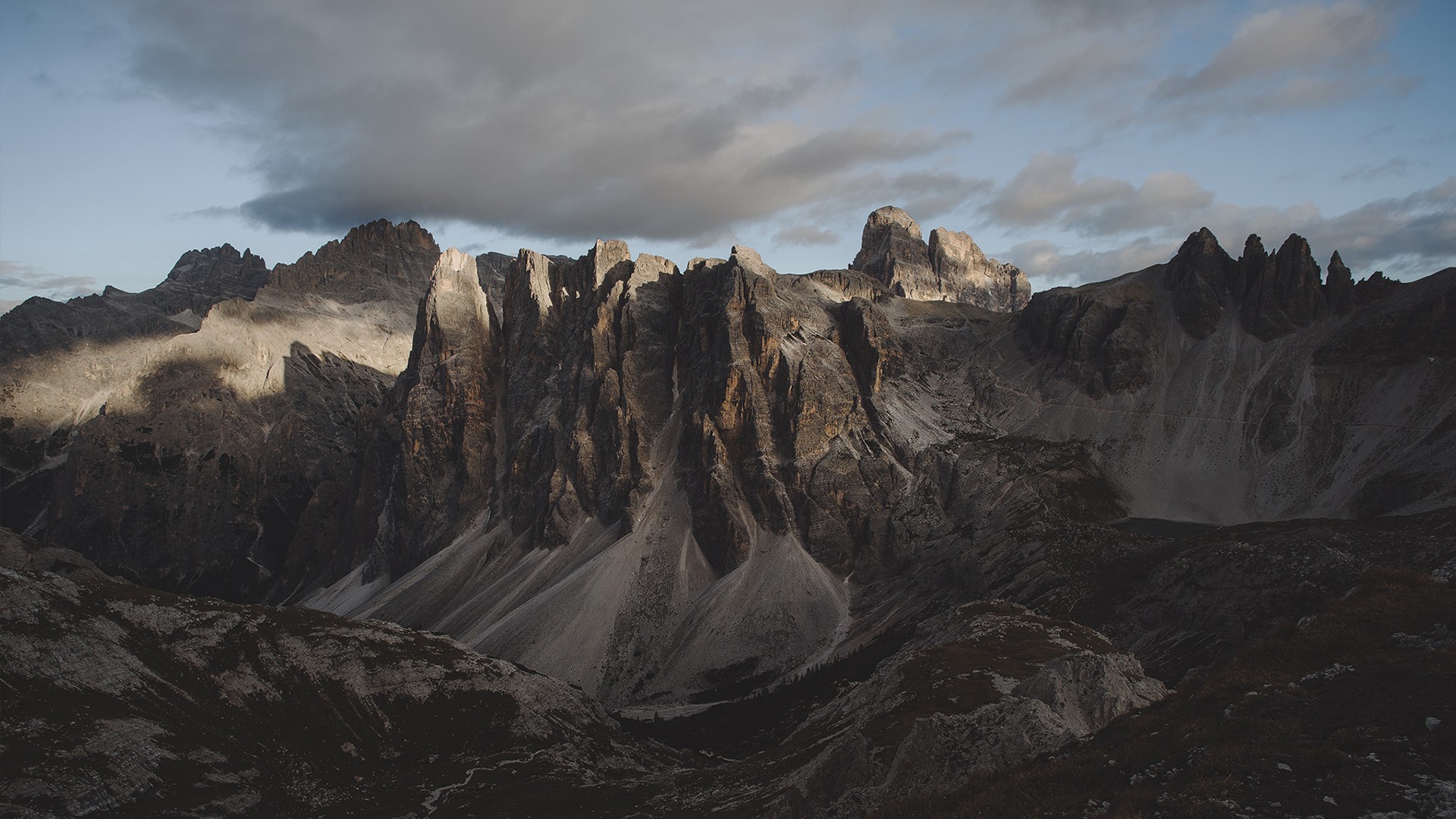 Jagged mountain peaks under a cloudy sky HD Wallpaper