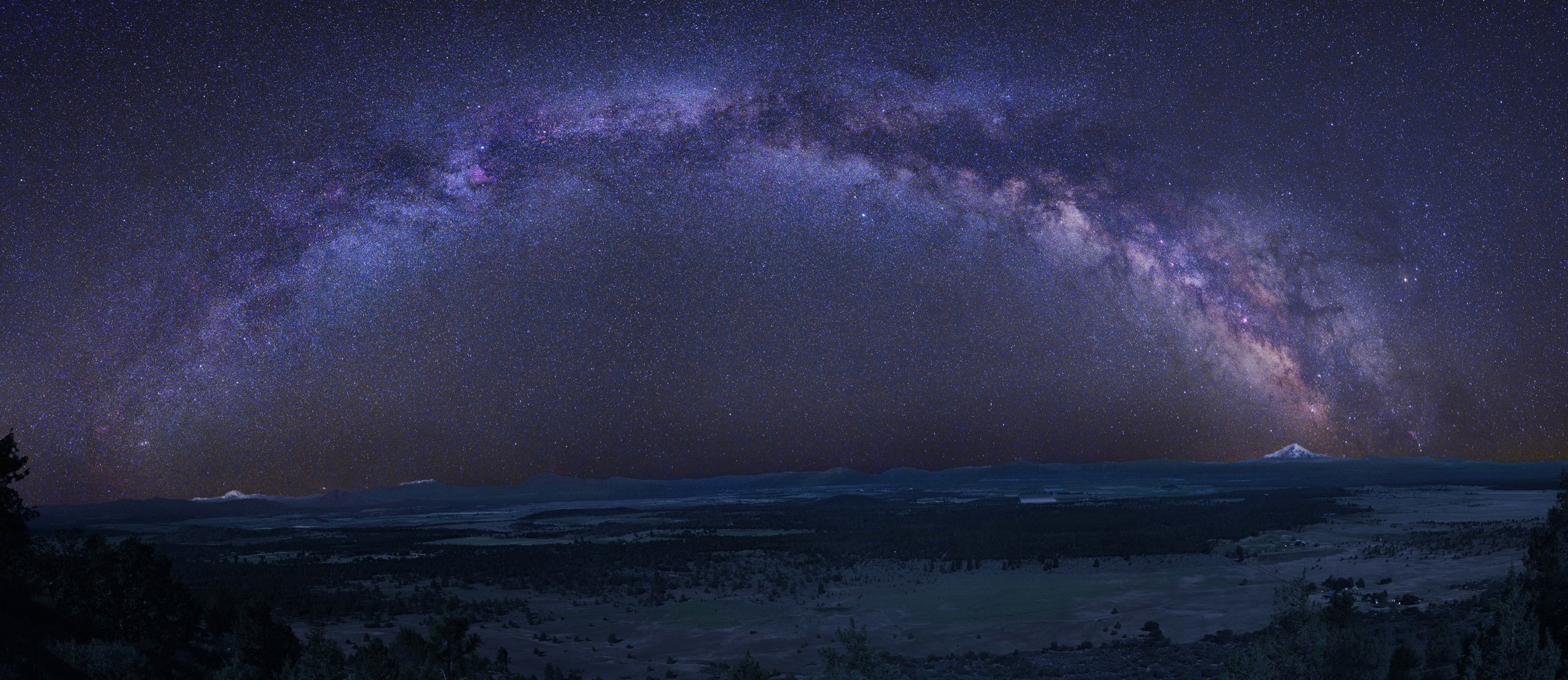 The Milky Way galaxy arches over a mountain landscape HD Wallpaper