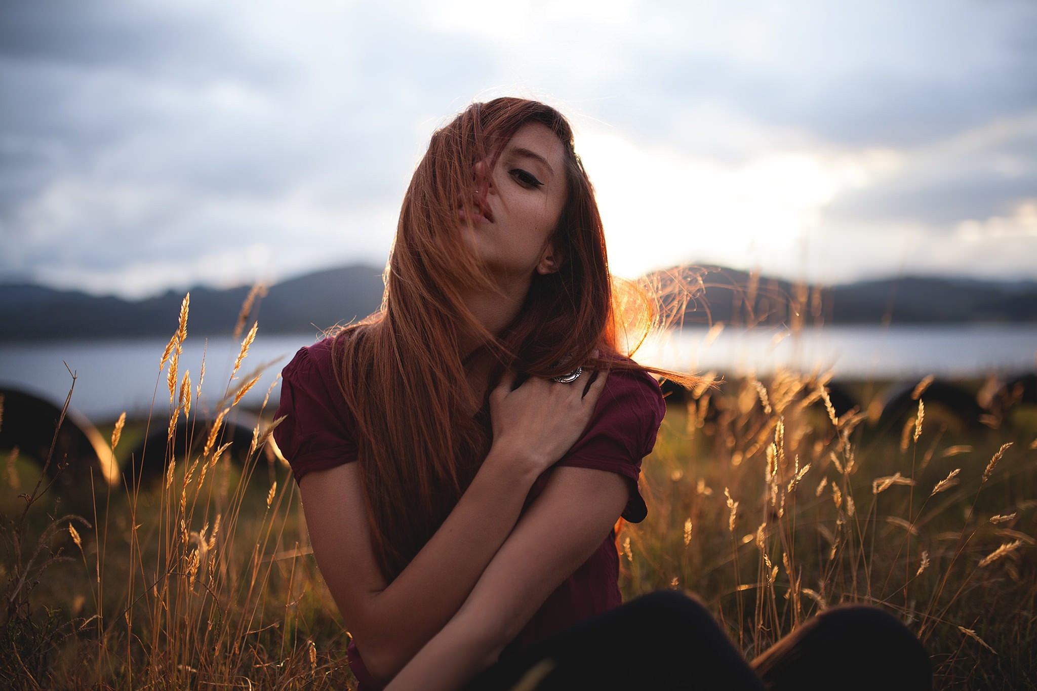 Woman with red hair sitting in a field at sunset HD Wallpaper