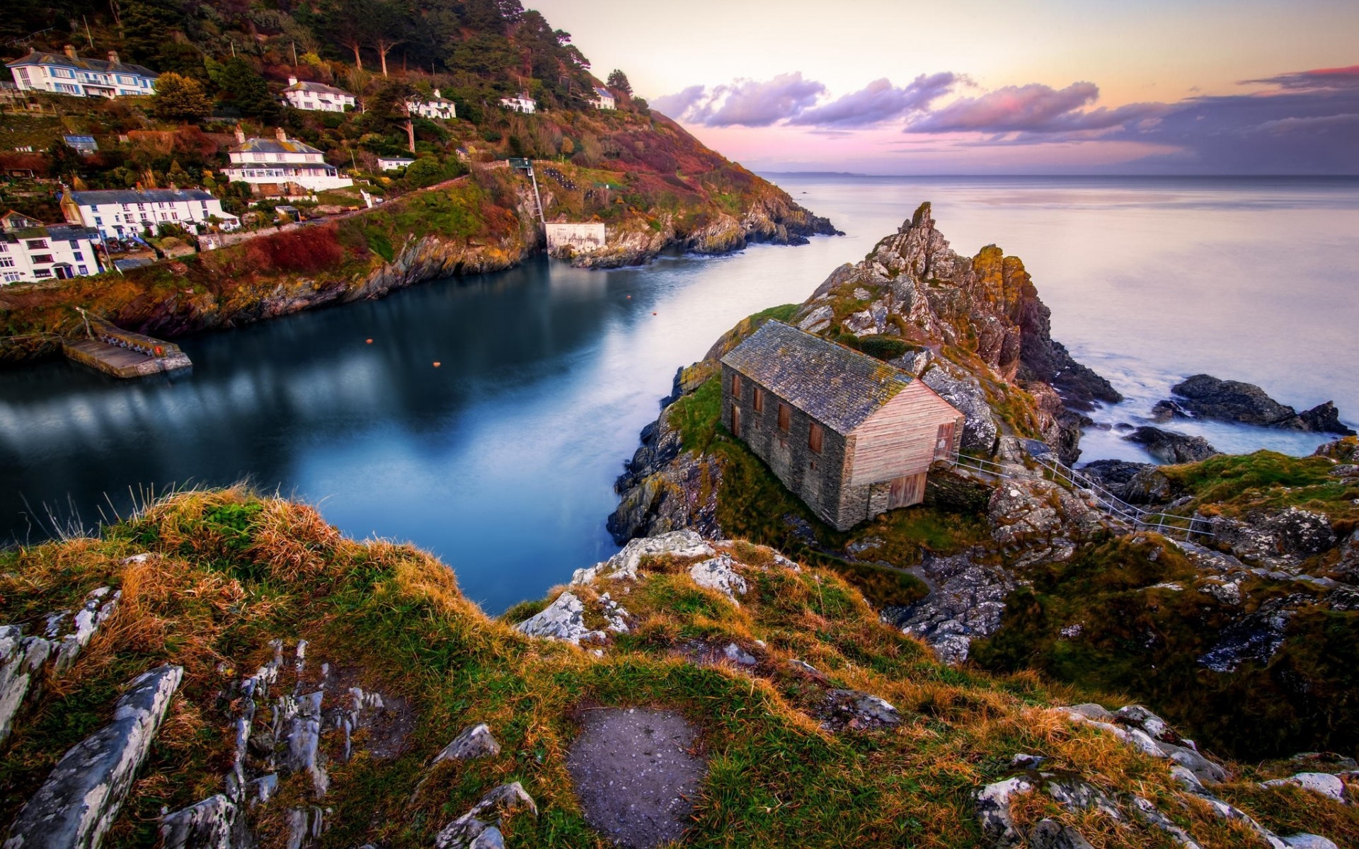 Coastal village with a boathouse on a rocky outcrop HD Wallpaper