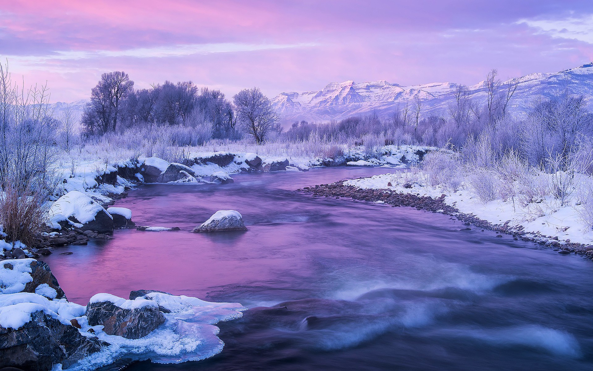 Winter river flowing through snow-covered landscape with mountains HD Wallpaper