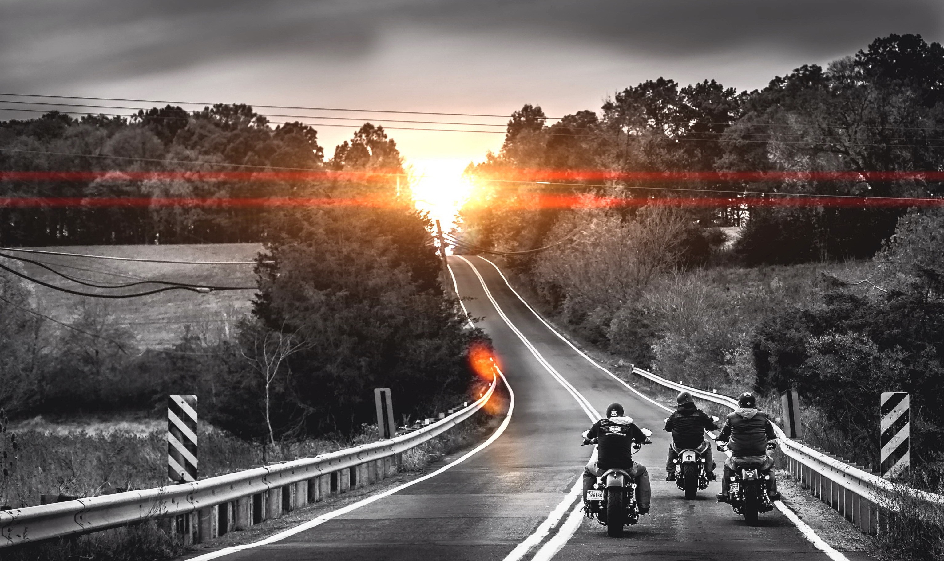 Motorcyclists ride on a road at sunset HD Wallpaper