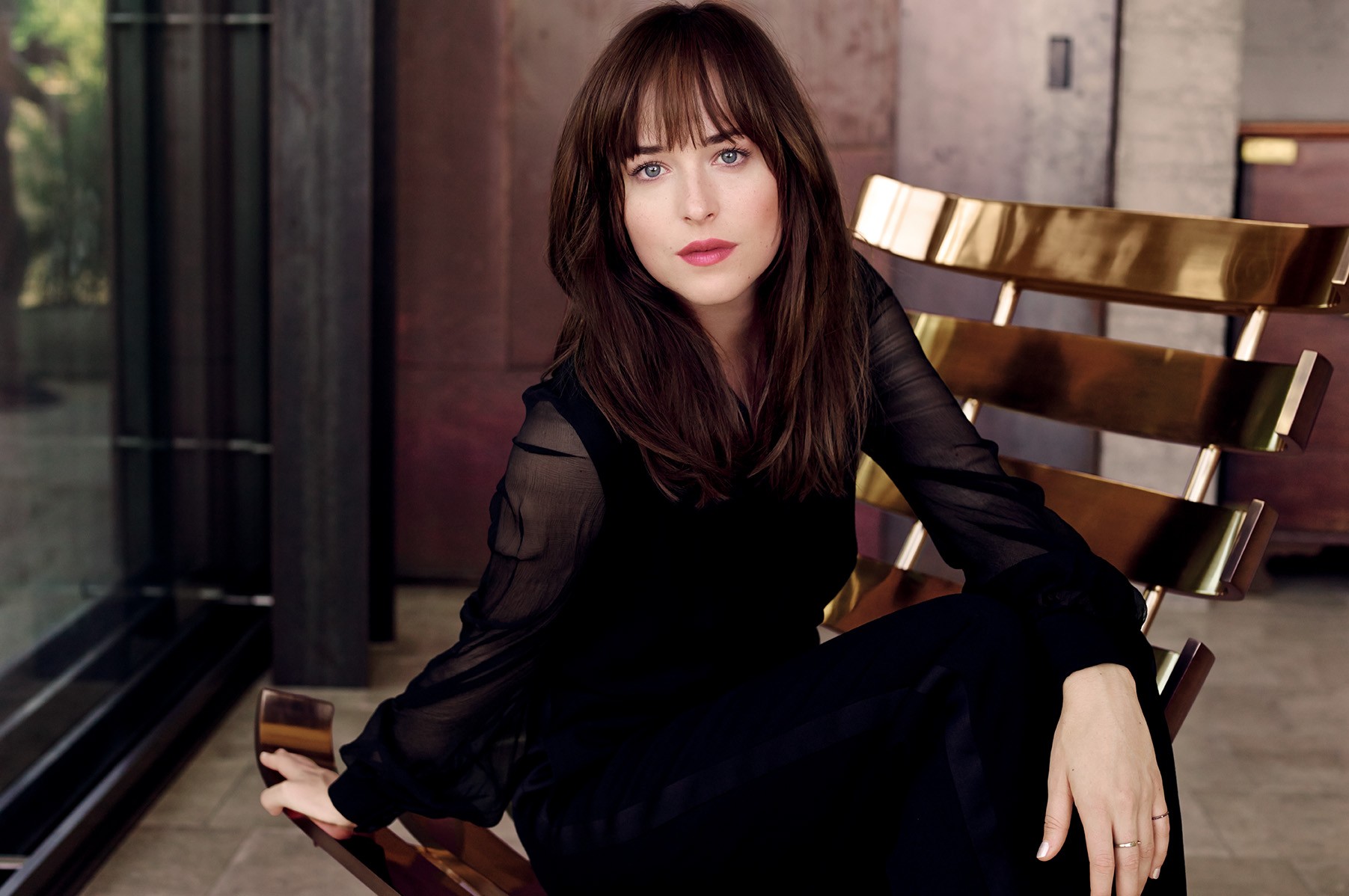 Dakota Johnson in a black dress sitting on a chair HD Wallpaper