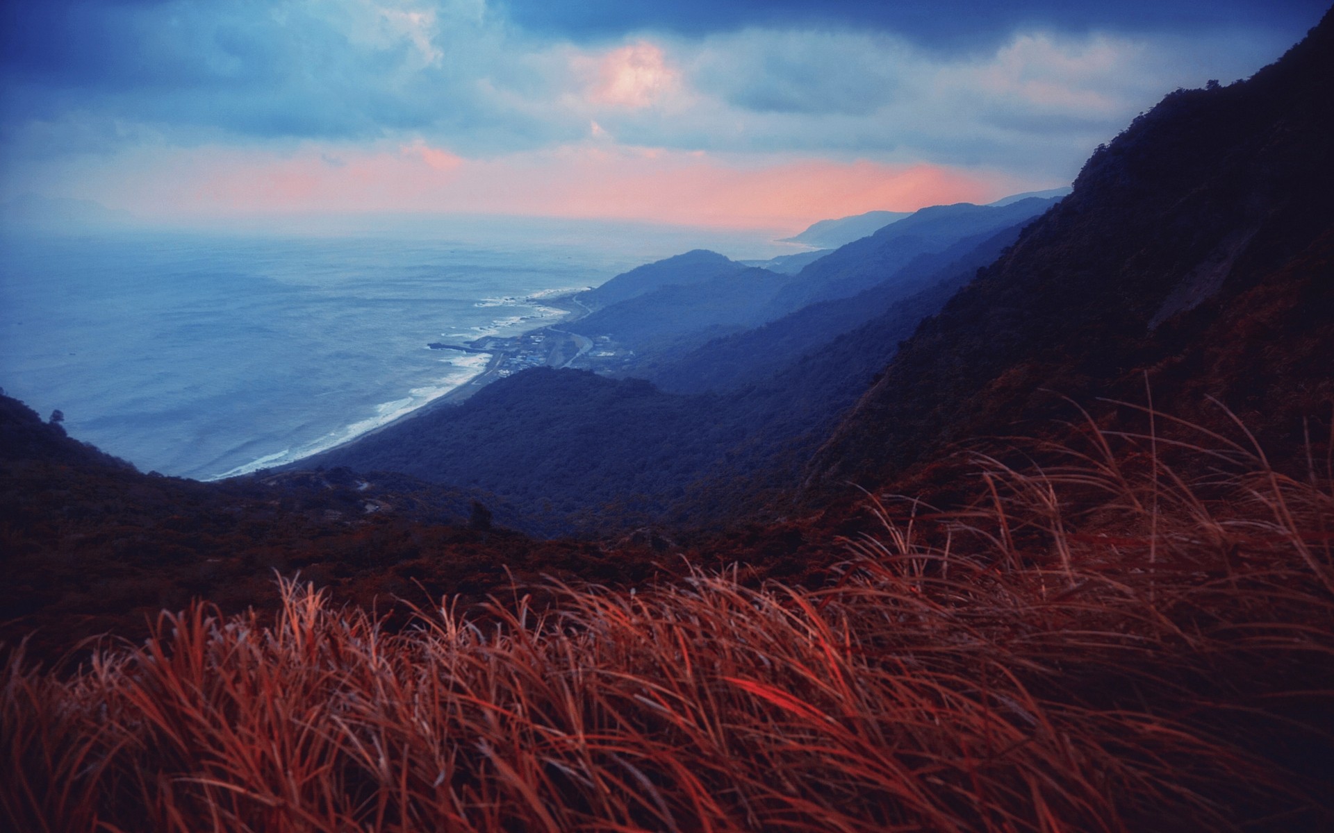 Coastal mountains and sea at sunset with red grass HD Wallpaper
