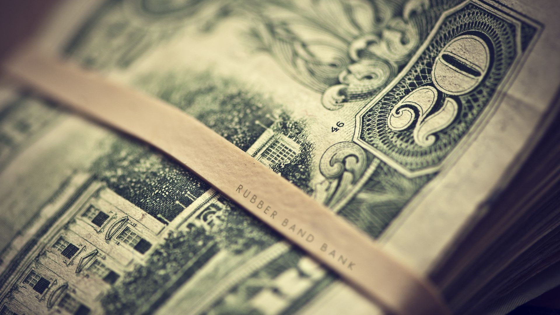 Close-up of a rubber band around a stack of US dollar bills HD Wallpaper