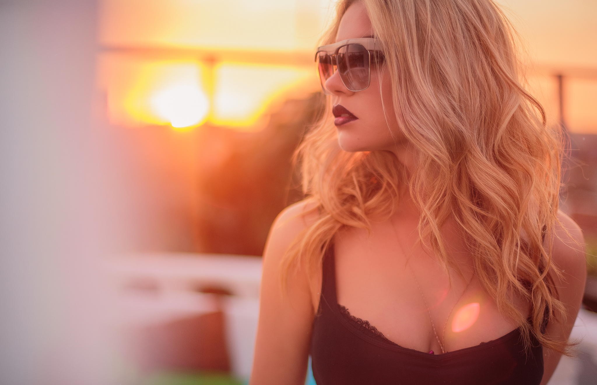 Woman with blonde wavy hair wearing sunglasses and black top at sunset HD Wallpaper