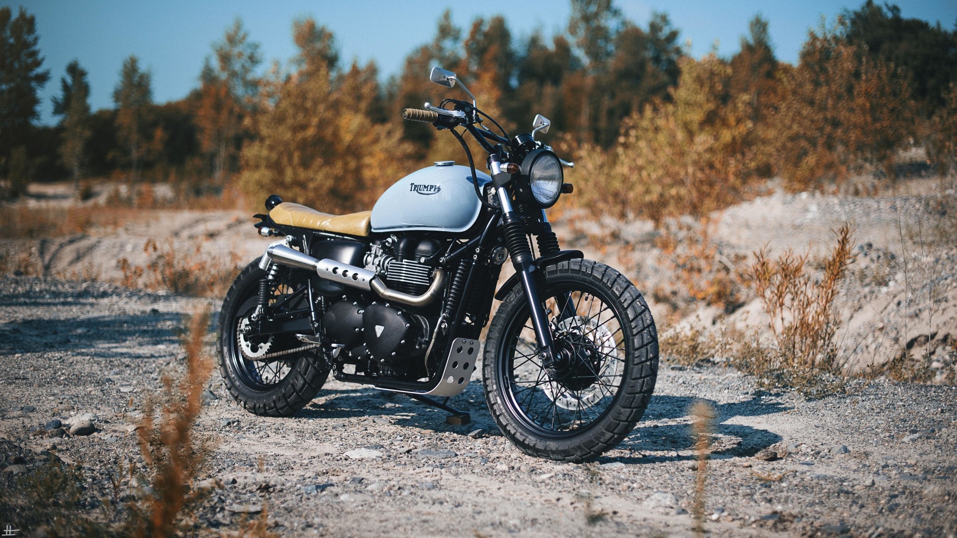 Triumph motorcycle parked on a dirt road HD Wallpaper